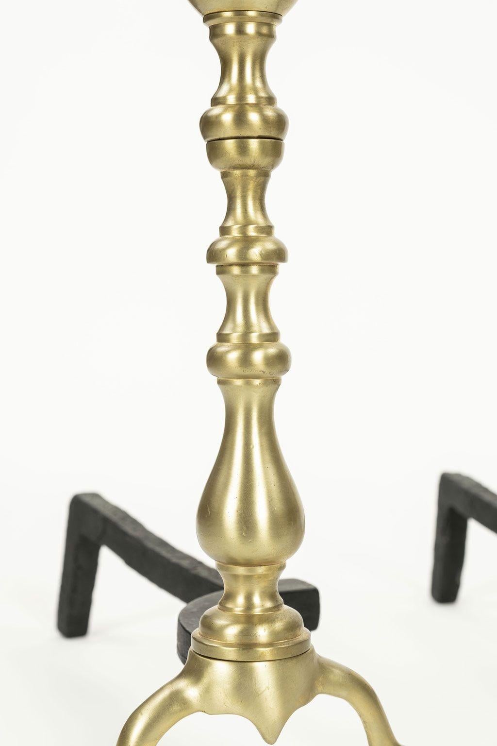 Pair of Georgian andirons in brass and iron circa 1770-1800. Georgian style andirons with polished brass turned uprights and pad feet. Wonderful aged patina on rear iron portions of andirons.