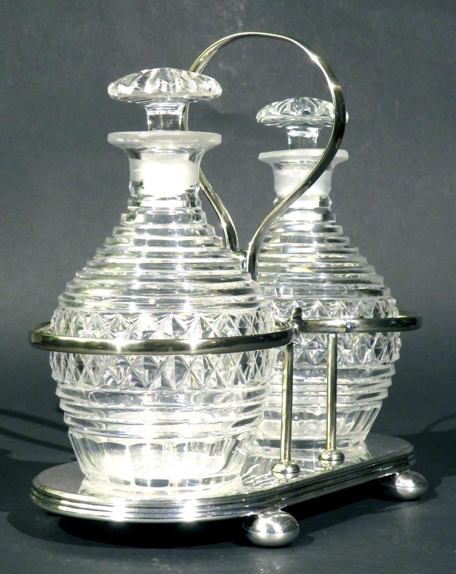 A very handsome pair of early 19th century cut glass spirit decanters, both greyish glass bodies of barrel shape, decorated with a broad band of wheel-cut diamond shaped facets, rising to multi-ringed necks & fitted with their original radial cut