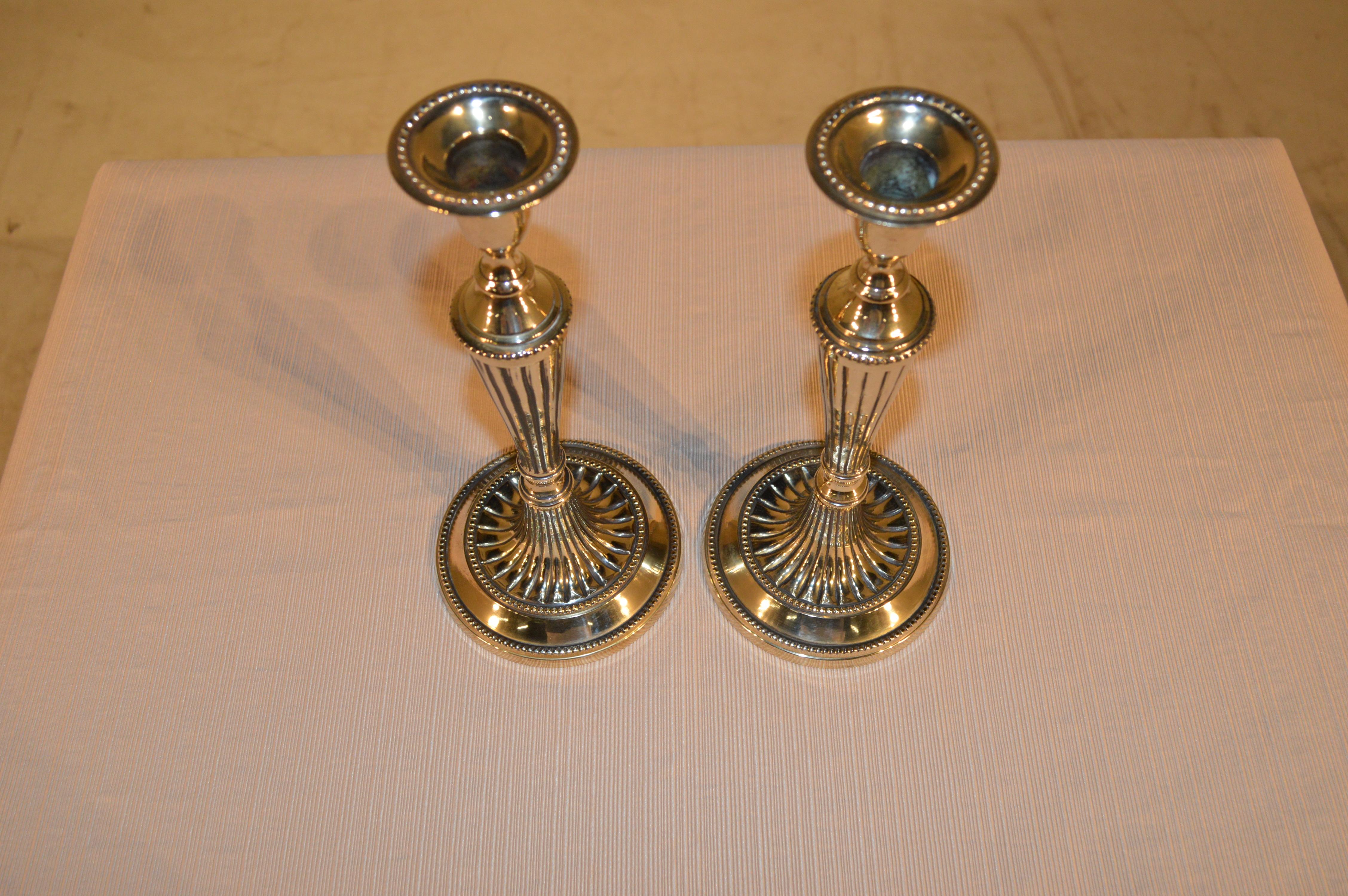 Late-18th century pair of Georgian brass candlesticks. They are hand cast and have lovely tulip-shaped candle cups following down to gracefully reeded stems and highly detailed bases.
