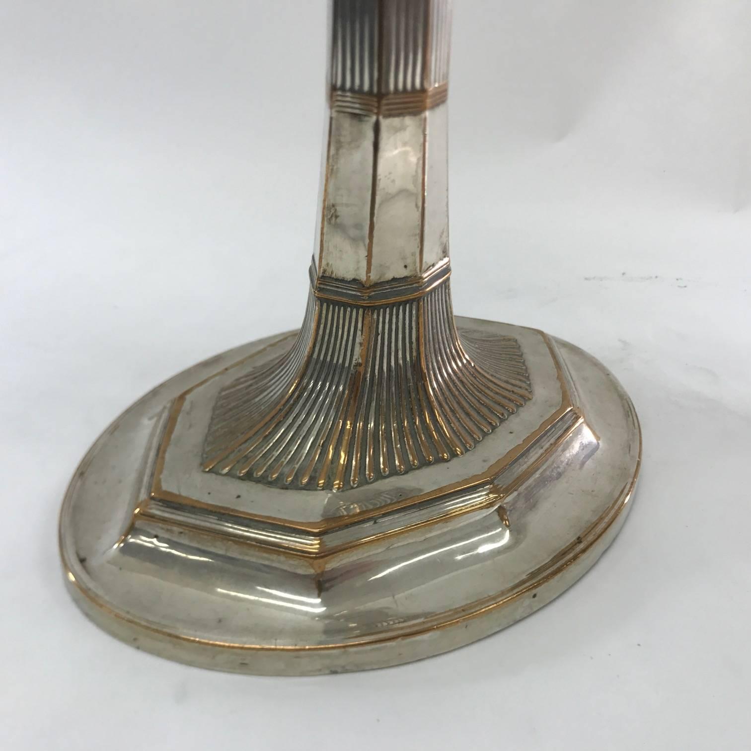 Particular pair of candlesticks in old Sheffield plate in George III style. On the base of oval shape there is an octagonal step, to it is connected a stem always with octagonal profile, also the upper part of the candlesticks takes up the shape of