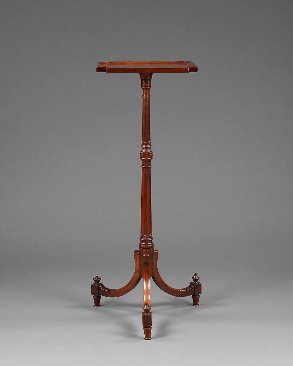 An elegant pair of Georgian mahogany candle stands, each raised on three out-swept legs, supported by a long-turned carved column holding a square shape tray. English, circa 1800.
