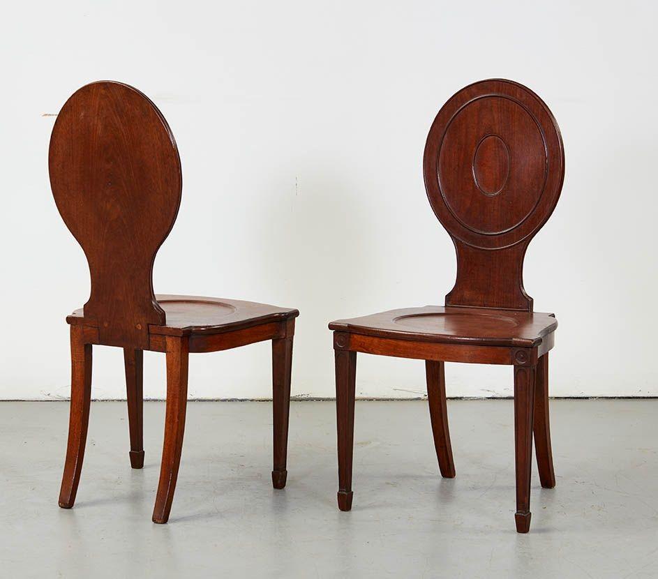 Pair of George III mahogany hall chairs, in the manner of and possibly attributable to Thomas Chippendale, the oval backs with molded panels, the shaped seats with curved fronts over square tapered legs having panel and rosette carvings. For some