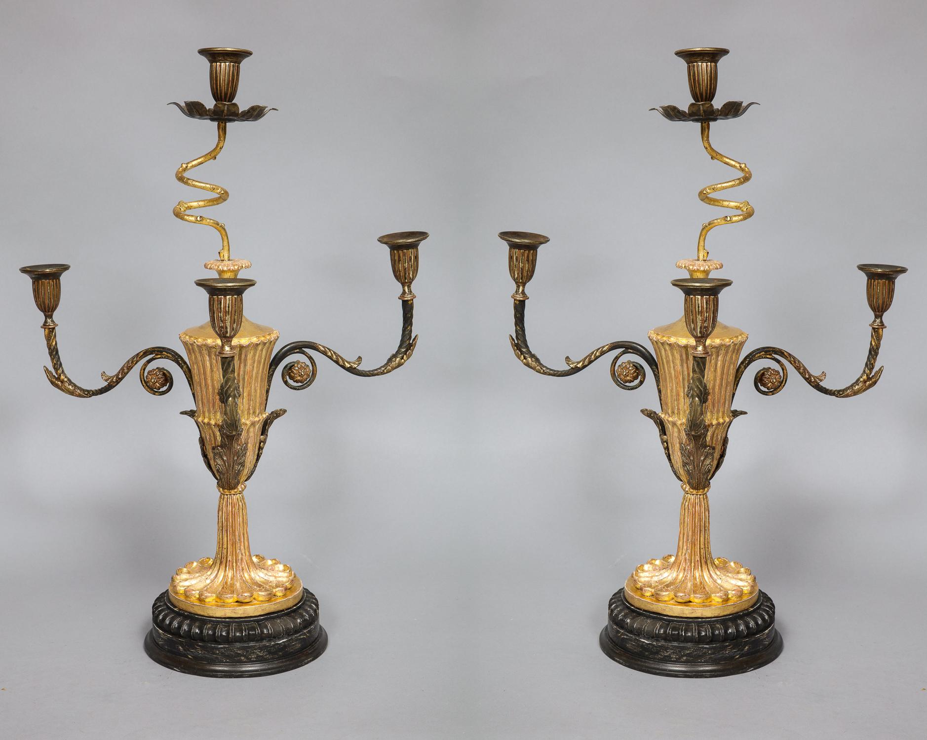 Fine pair of George III carved and giltwood candelabra in the manner of Thomas Chippendale the Younger, the four candle sockets with ribbed sides, the central arm with corkscrew shaft having later drip pan, the three side lights with fire gilt brass