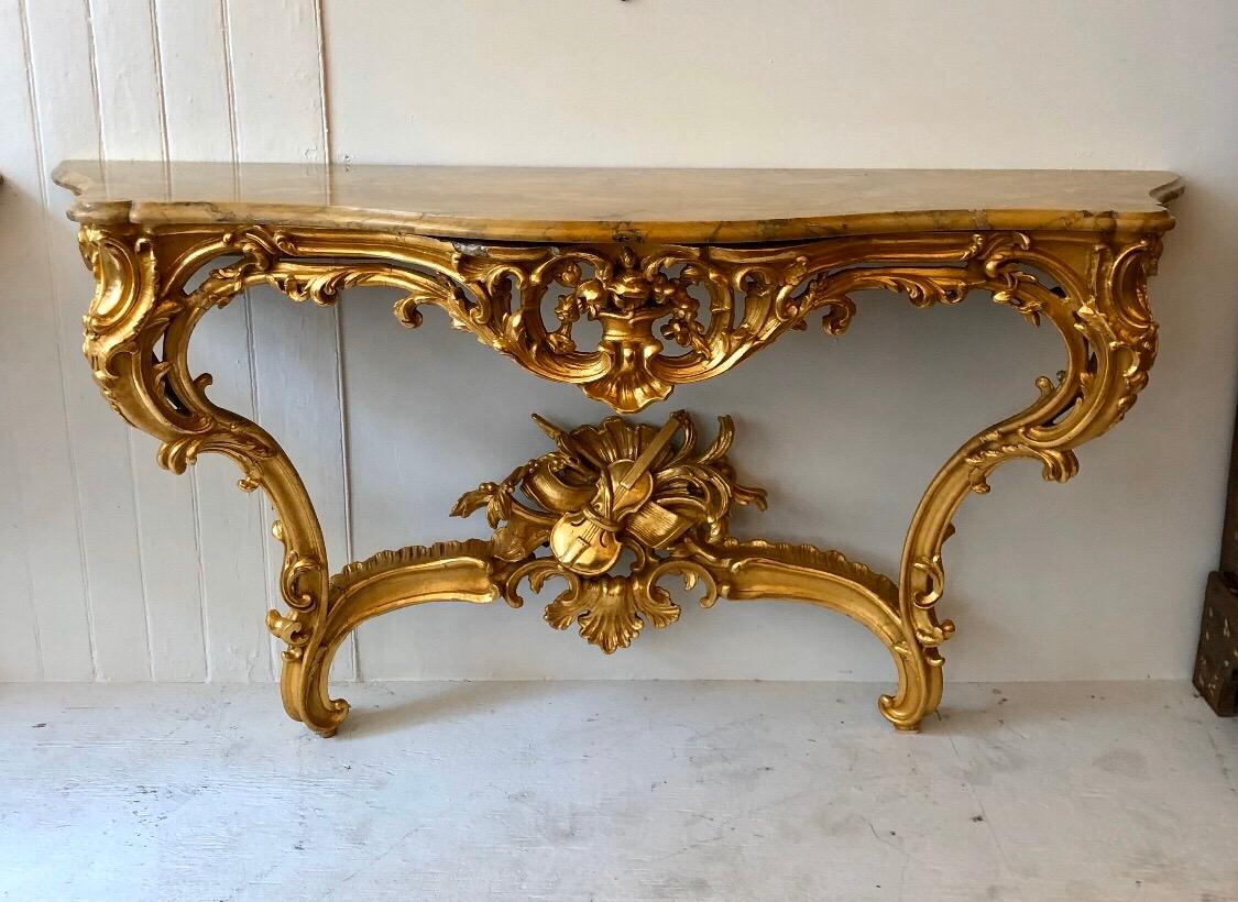 This Grand pair of Irish Rococo consoles have carved gilded wood cabriole legs and intricate carved stretchers with musical motifs.
