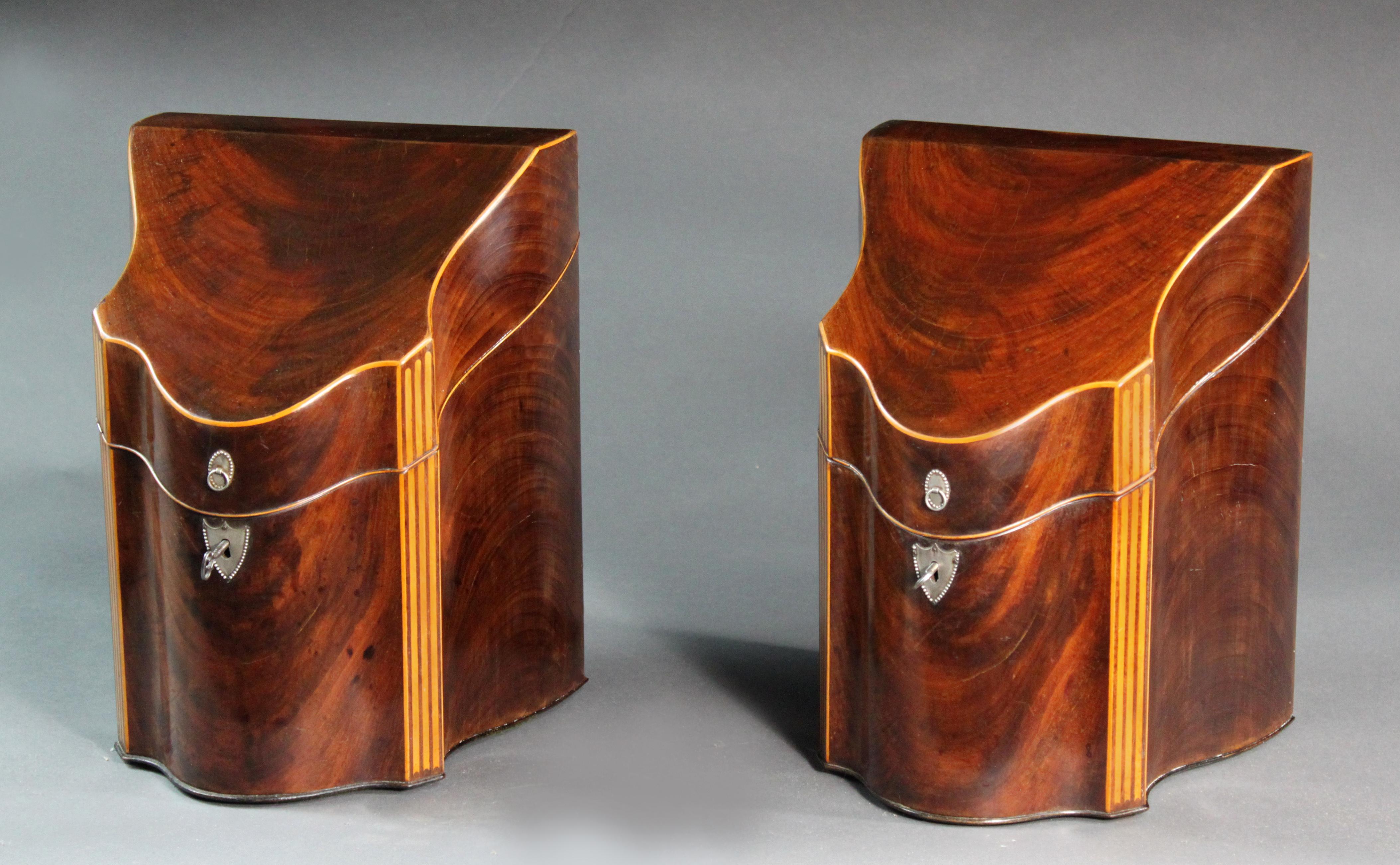 Fine pair of George III Sheraton Period figured mahogany knife boxes with striking boxwood stringing, silver plated mounts and the original fitted interiors. We have never seen serpentine sides on a knife box before and together with the serpentine