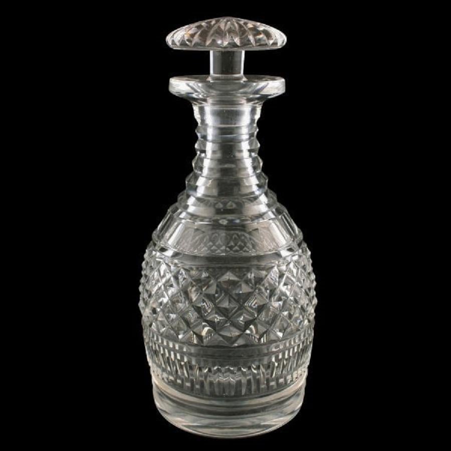 A pair of early 19th century Georgian heavily cut glass decanters.

The decanters have a heavily cut body, a facet and ridge cut neck and a ground pontil mark to the base.

The decanters have mushroom shaped stoppers that are star cut to the