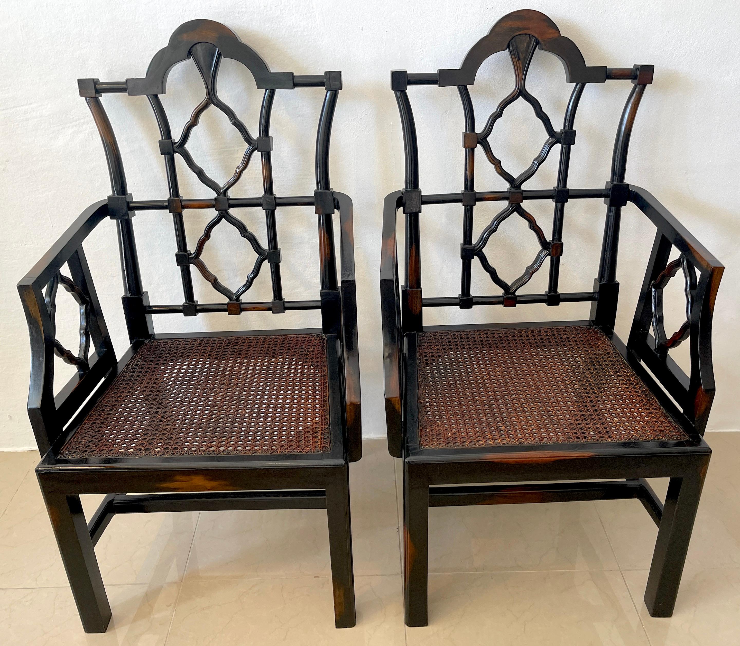 Pair of Georgian style Chinese chippendale arm chairs, Each one of generous proportions, with pagoda back rests, pierced diamond armrests, cane seat. Complete with a custom ebonized finish with intentional light spots, resembling cowhide. Raised on