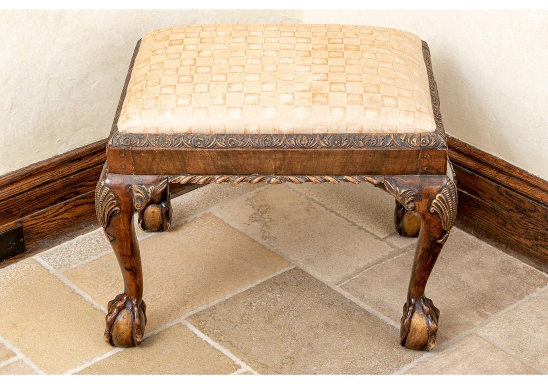 Pair of Georgian style leather benches with distressed patterned leather upholstery, web construction, carved perimeter, heavily carved legs with shell motif and resting on ball and claw feet.
Dimensions: 25 1/2