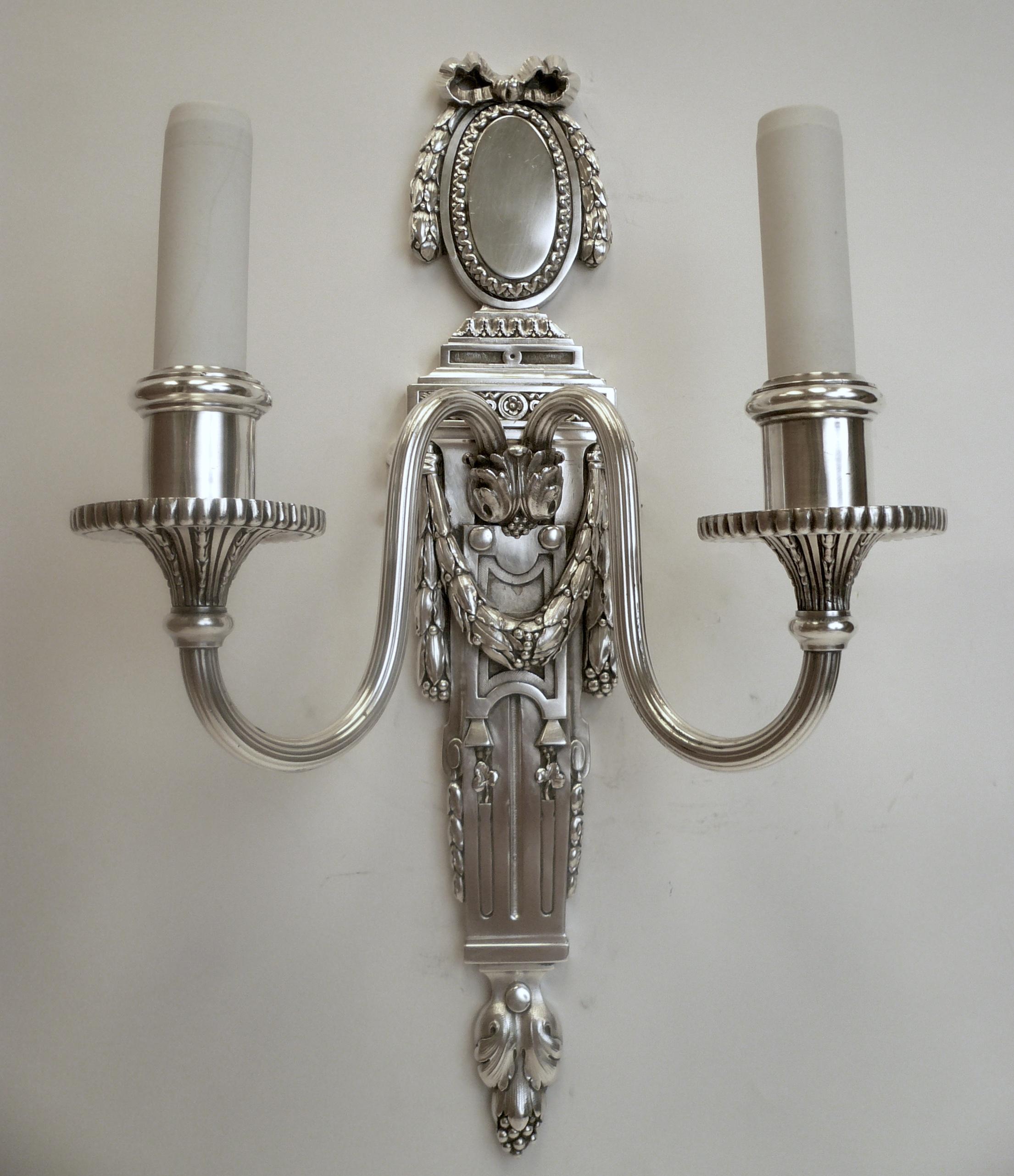 These handsome two light sconces in the Robert Adam style feature classical motifs including acanthus leaves, bowknots, and bellflowers.