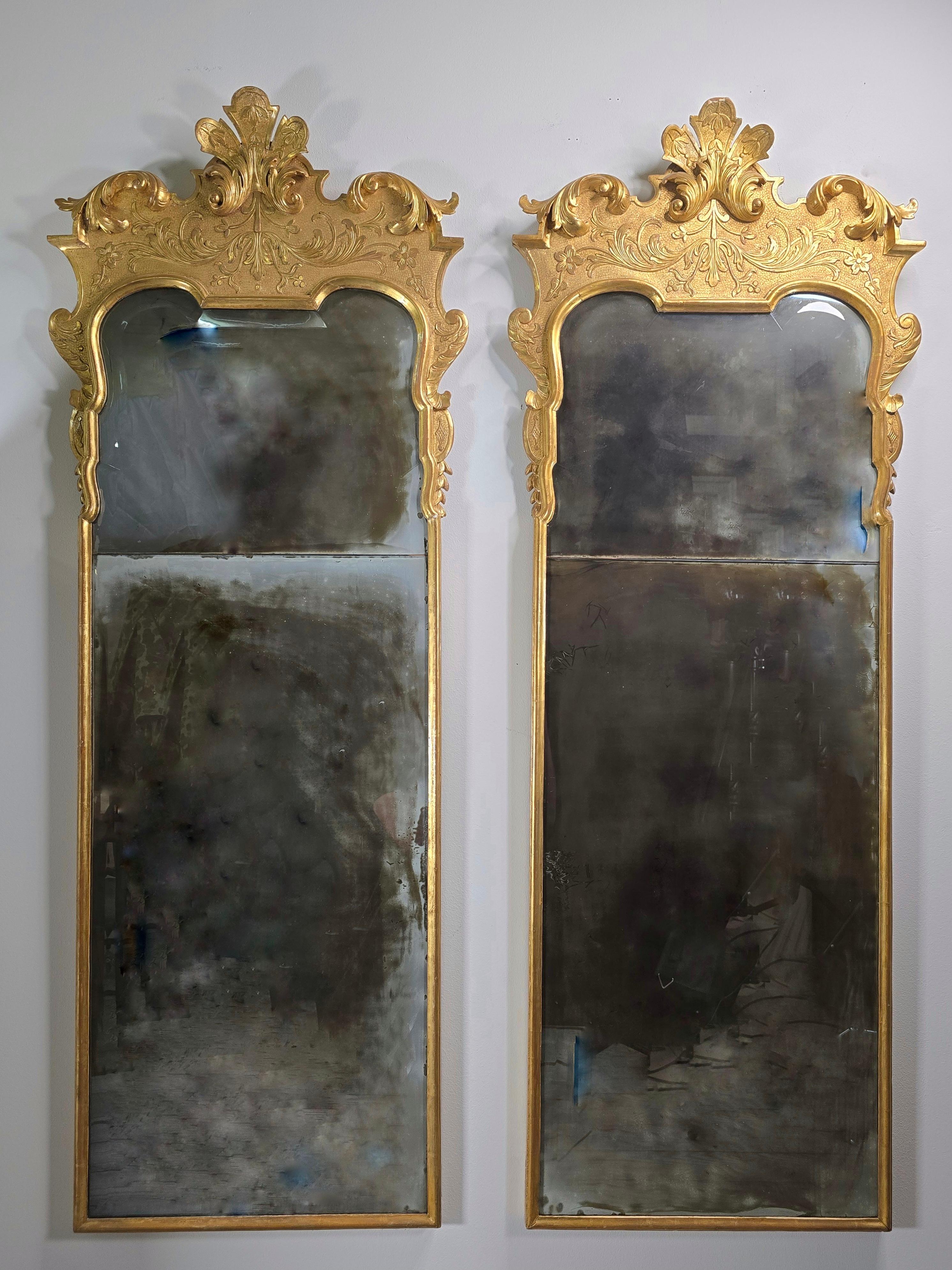 A very fine pair of George I style carved and gilt mirrors, in the manner of John Belchier.  The mirror has an elaborately carved gilt gesso frame.  The quali done innthe beginning half of the 20th century.   The glass in the mirror is hand beveled
