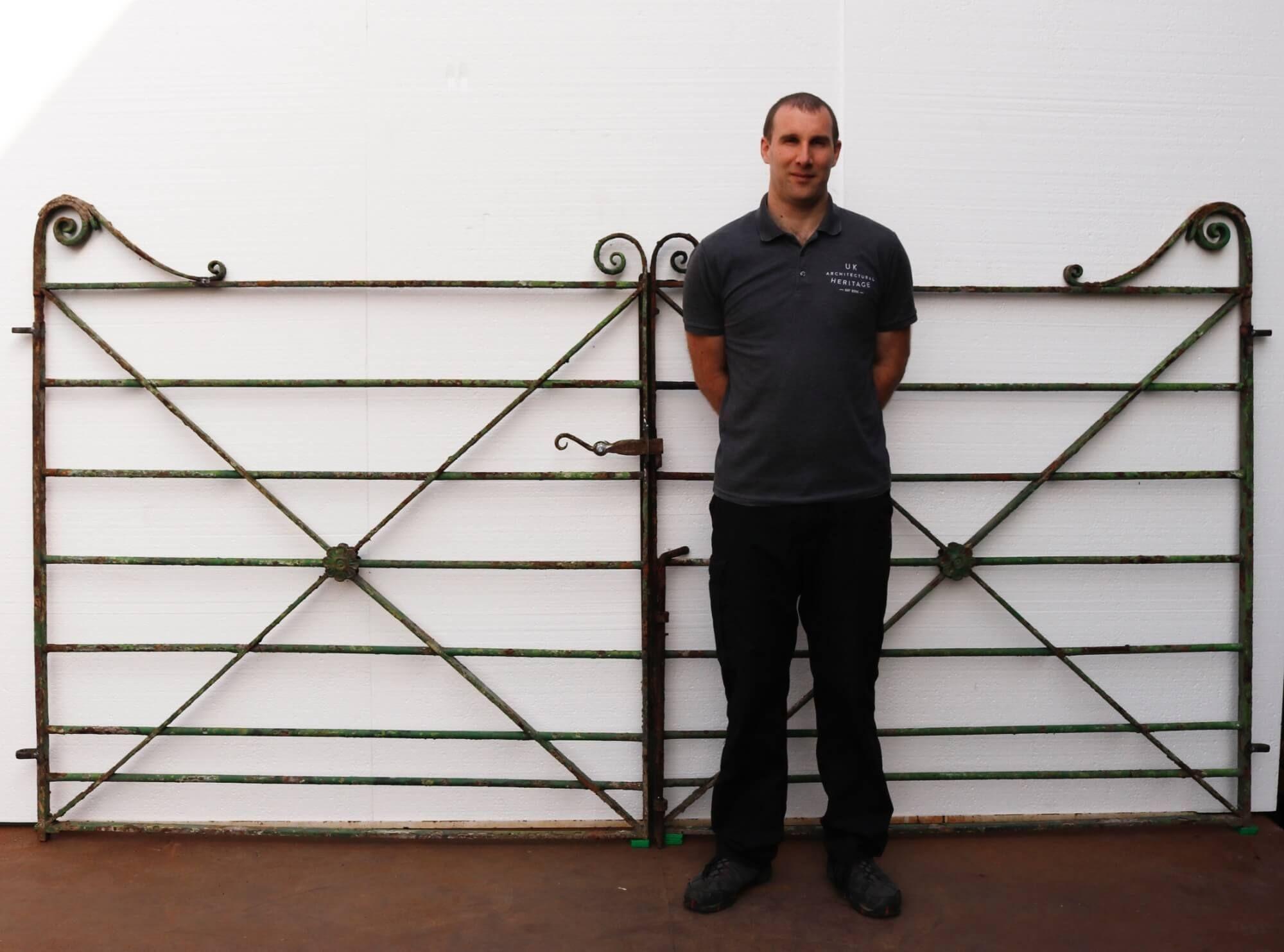 A pair of Georgian wrought iron estate gates with an original latch. This pair of impressive gates would stand out at a countryside home. With a flower in the centre and green finish match perfectly with its scrolling ends. This gate certainly