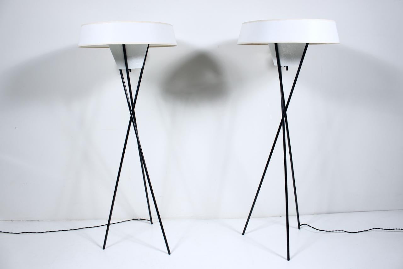 Pair of Gerald Thurston for Lightolier Tripod Floor Lamps in Black & White with Off White shades. 1950's. With three balanced and supported tubular black enameled metal legs, original feet, perforated white cone diffusers. With perforated top