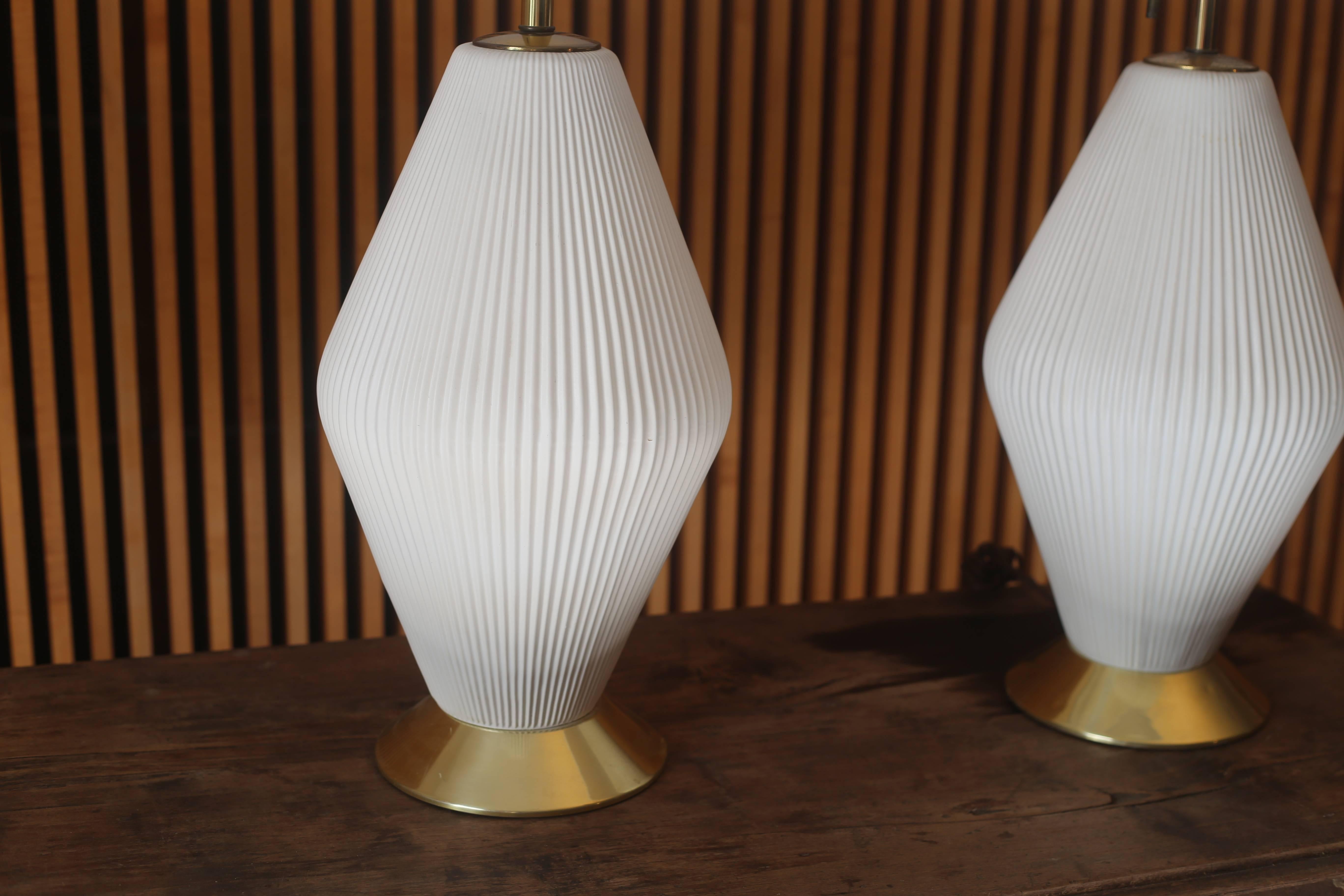 Exceptional and scarce pair of table lamps designed by Gerald Thurston for Lightolier. Pleated ceramic bodies supported by a brass base and with triple sockets to provide desired levels of lighting. 

Dimensions:
36