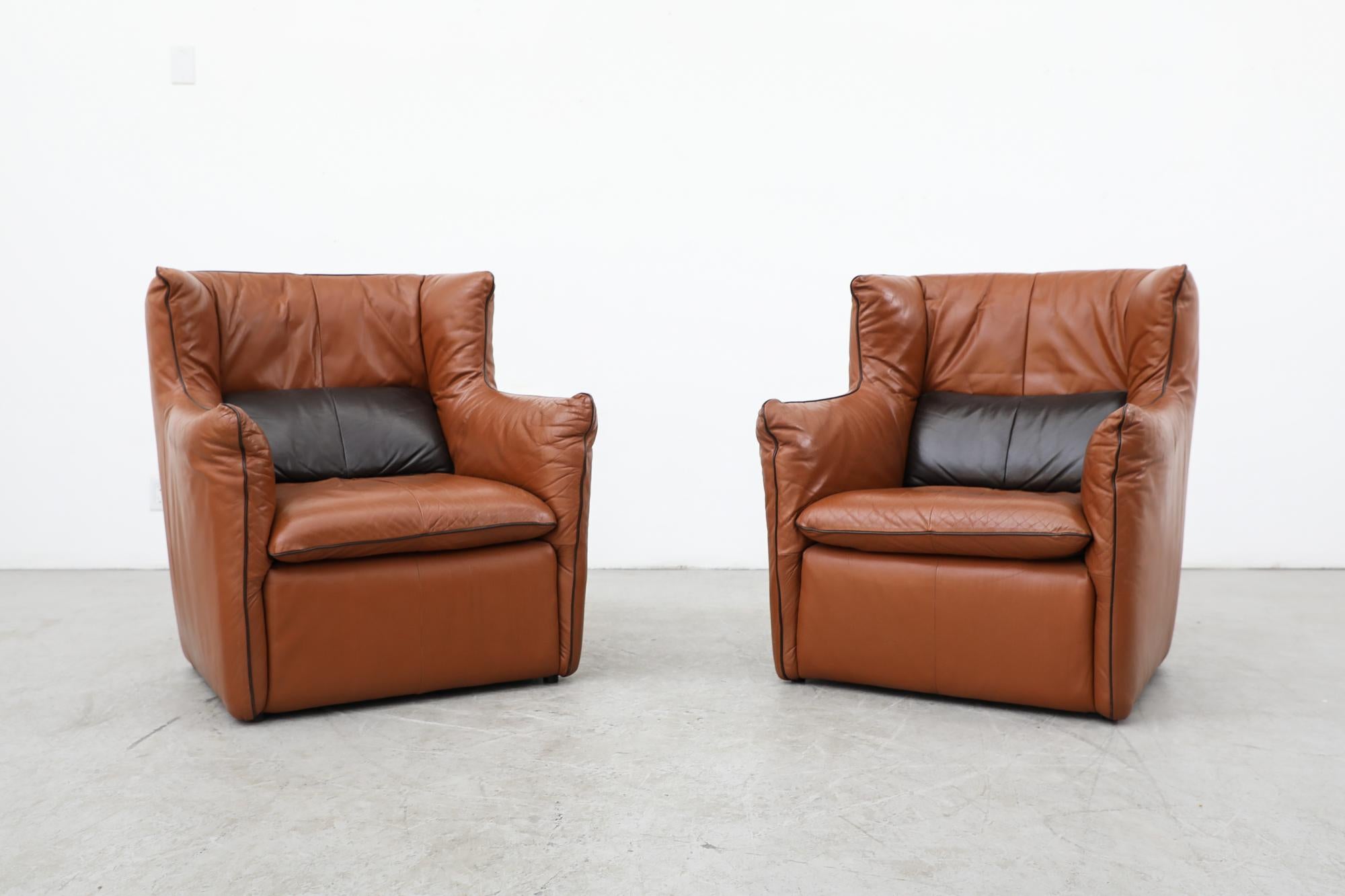 Pair of gerard van den Berg high back cognac leather lounge chairs with dark chocolate leather piping and buttoned on back pillows. Lovely patina to both lounge chairs. In original condition with wear consistent with their age and use. Set price.
 
