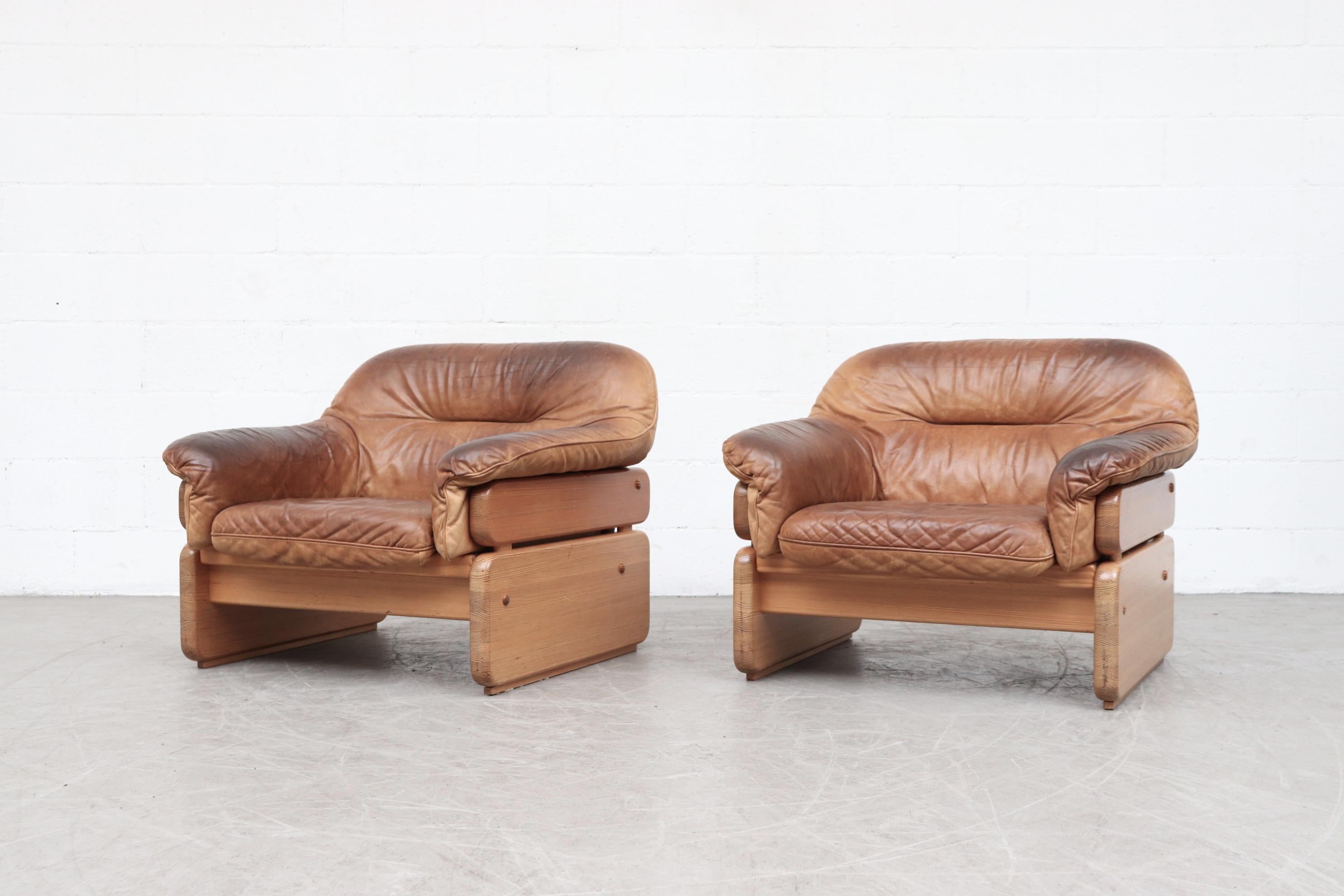 Handsome pair of pine and leather lounge chairs. Beautifully worn with a nice patina. In original condition with visible signs of wear consistent with age and use. Set price. Color may vary from photo.