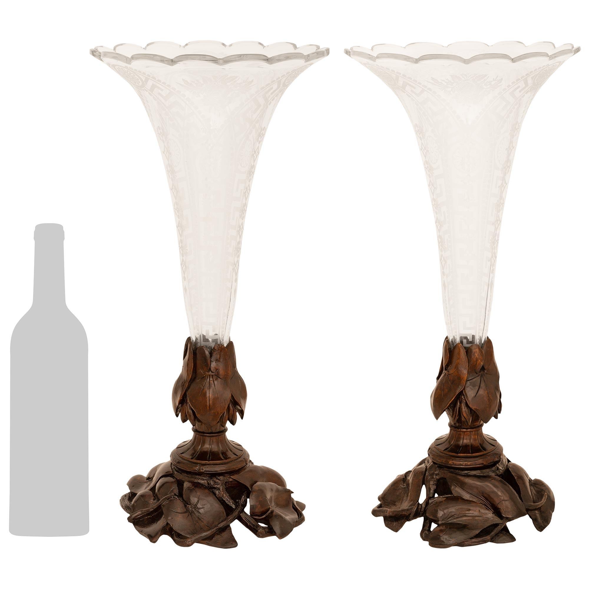 An elegant pair of German 19th century Black Forest st. etched Glass and Walnut vases. Each beautiful vase is raised on a wonderful array of Walnut water flora below a fluted socle shaped support with additional foliage wrapped around the base of