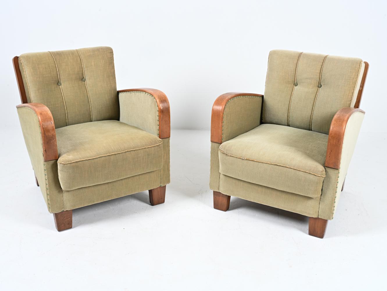 Born of the hands of a skilled carpenter, this fabulous pair of Art Deco club chairs features a chunky silhouette crafted from solid beech wood, with dramatically curved arm pads and unique partially-exposed back stiles and crests. The seats are