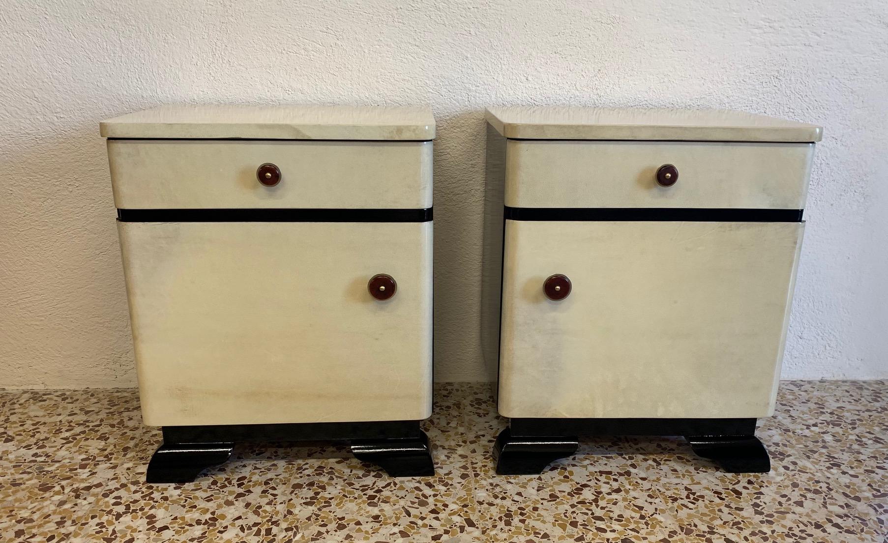 These Art Deco bedside tables were produced in the 1940s in Germany.
The front and the top are covered with parchment while the base and the sides are black lacquered.
The special handles are in brass and Bakelite.