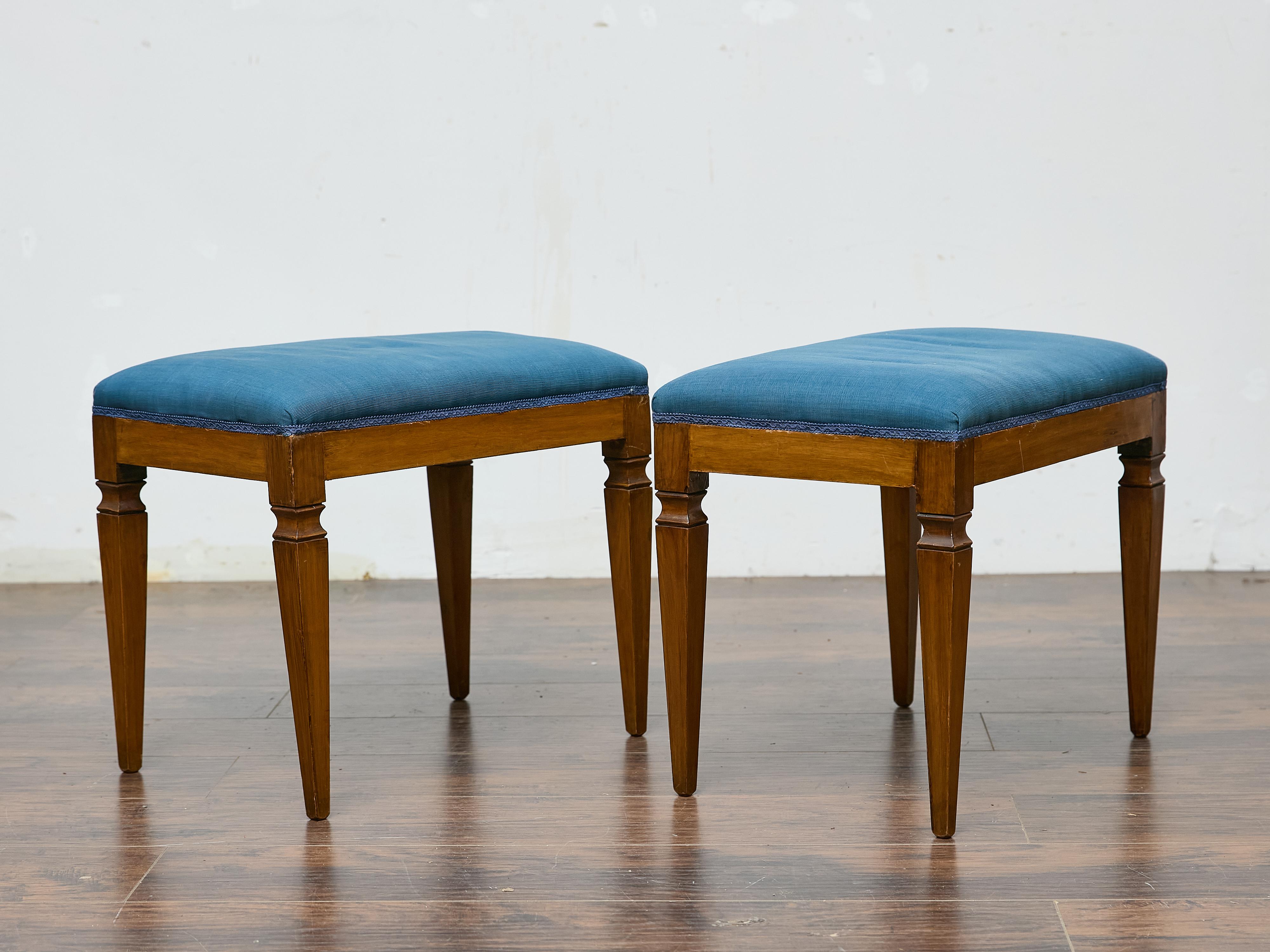 A refined pair of Biedermeier benches from the 19th century, exuding understated elegance with clean lines and restrained ornamentation. The solid wood frames are defined by tapered legs, subtly accented with linear carvings that enhance their