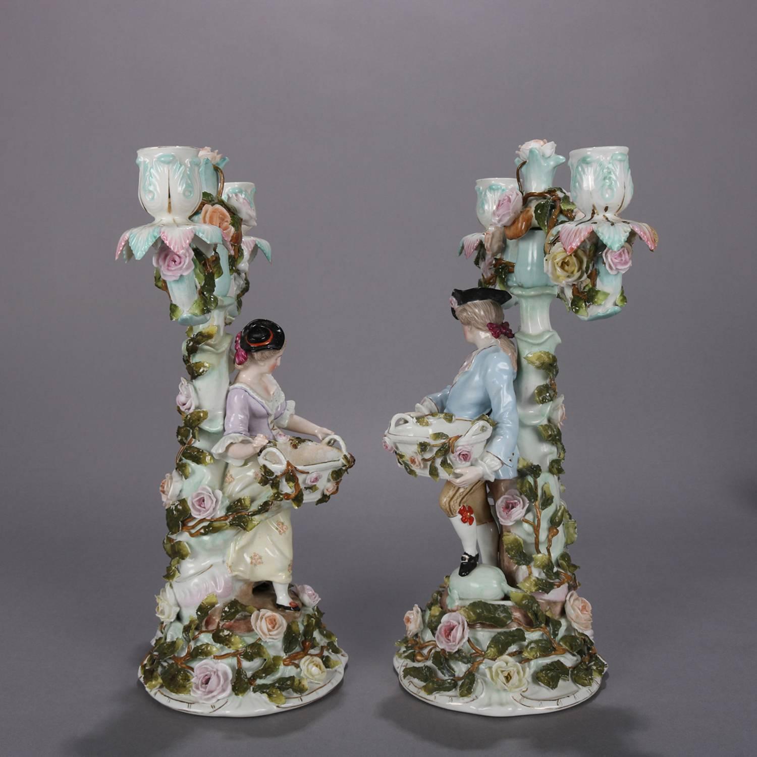 Pair of German Dresden figural porcelain candelabra feature bases with applied courting couple figures in rose garden setting raising three light candles with applied floral garland, see condition report and being sold as-is, marked 230 on base,