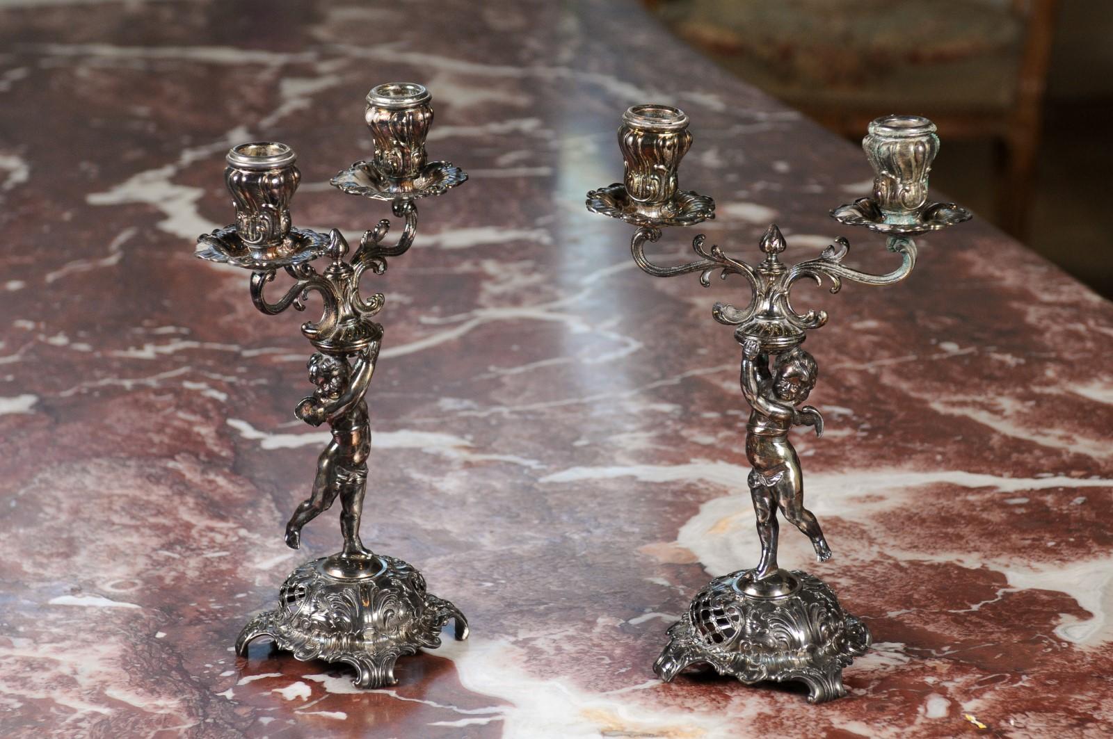A pair of German Jugendstil late 19th century silver plated candelabras from the Wurtemberg Metalware Factory, with cherubs holding the bobèches. Born in Germany in the Württembergische Metallwarenfabrik (WMF) during the last quarter of the 19th
