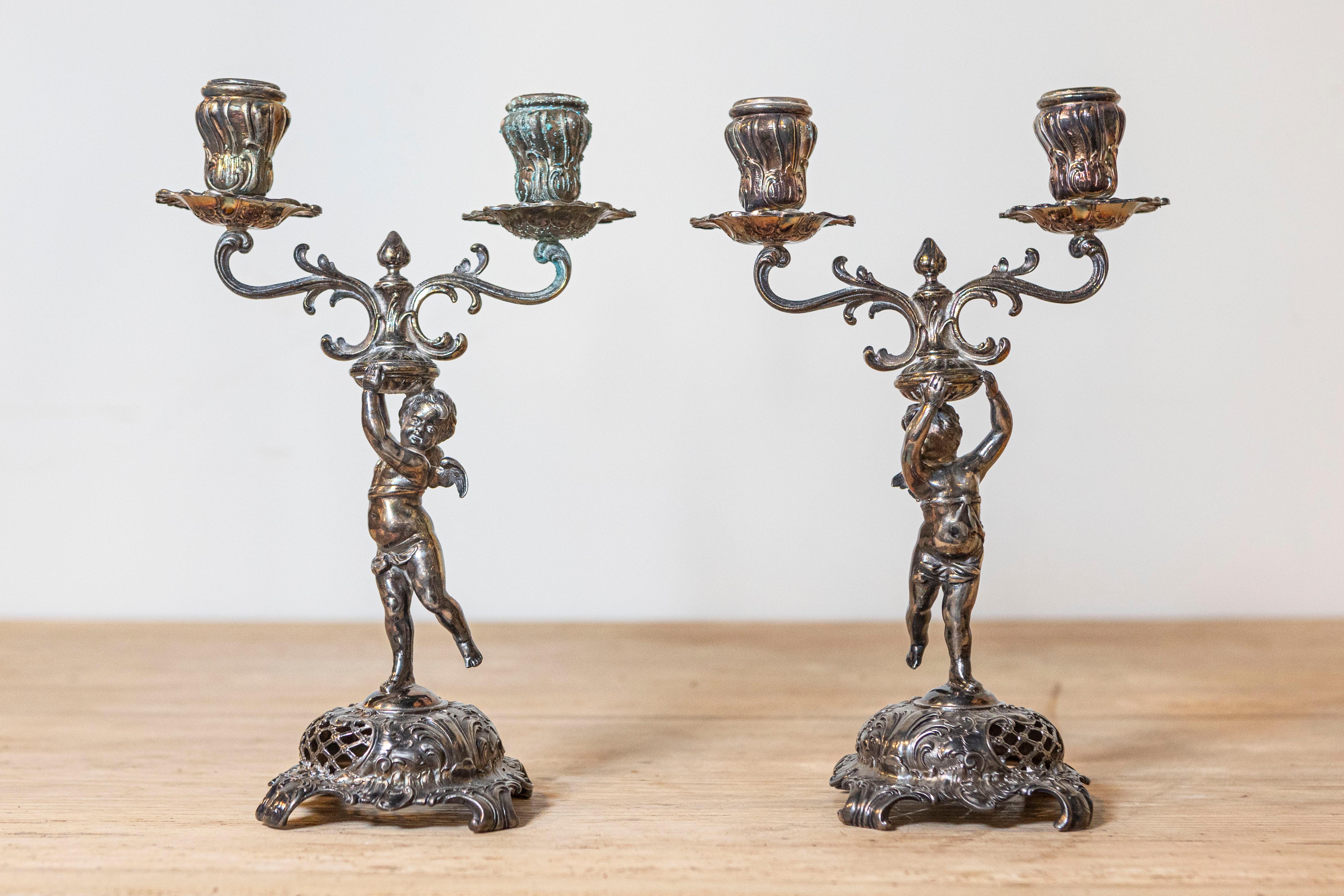 Coppia di candelabri tedeschi Jugendstil della fine del XIX secolo, placcati in argento e provenienti dalla Manifattura metallurgica del Wurtemberg, con putti che reggono i bobèches. Nata in Germania nella WMF (Württembergische Metallwarenfabrik)