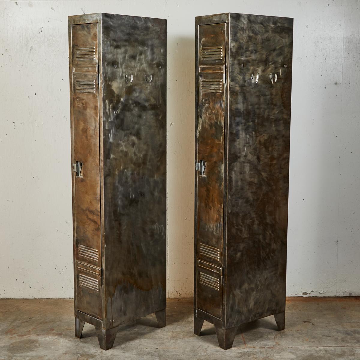A pair of tall narrow lockers with upper and lower vents, latch locks and angle cut feet.