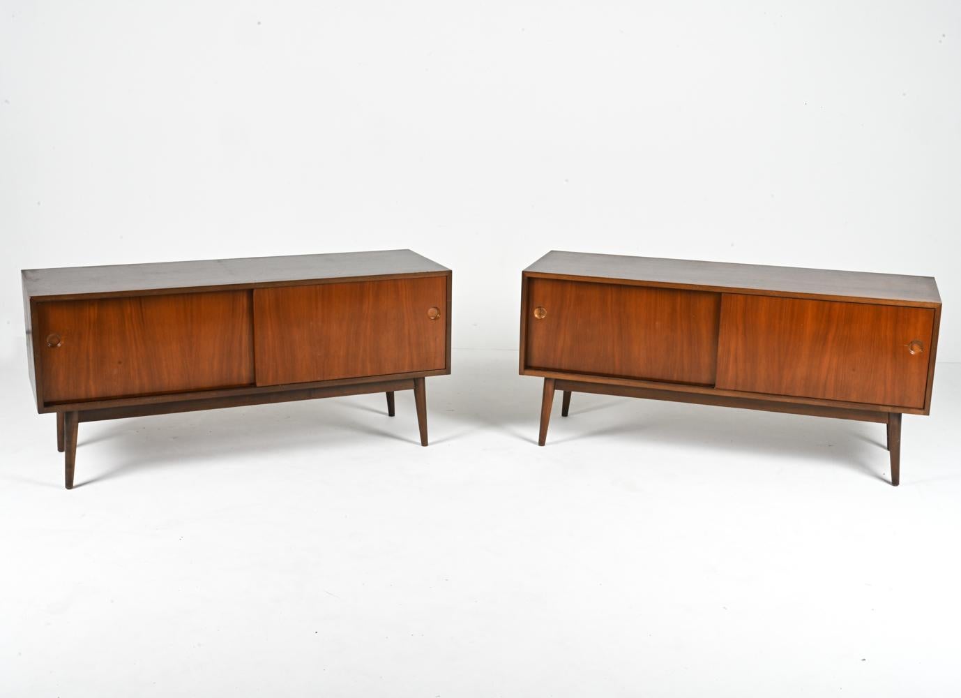 Plongez dans l'allure intemporelle du design du milieu du siècle avec cette paire exceptionnelle de meubles d'appoint. Méticuleusement fabriquées en Allemagne à partir de noyer luxueux, ces pièces allient harmonieusement la forme et la fonction pour