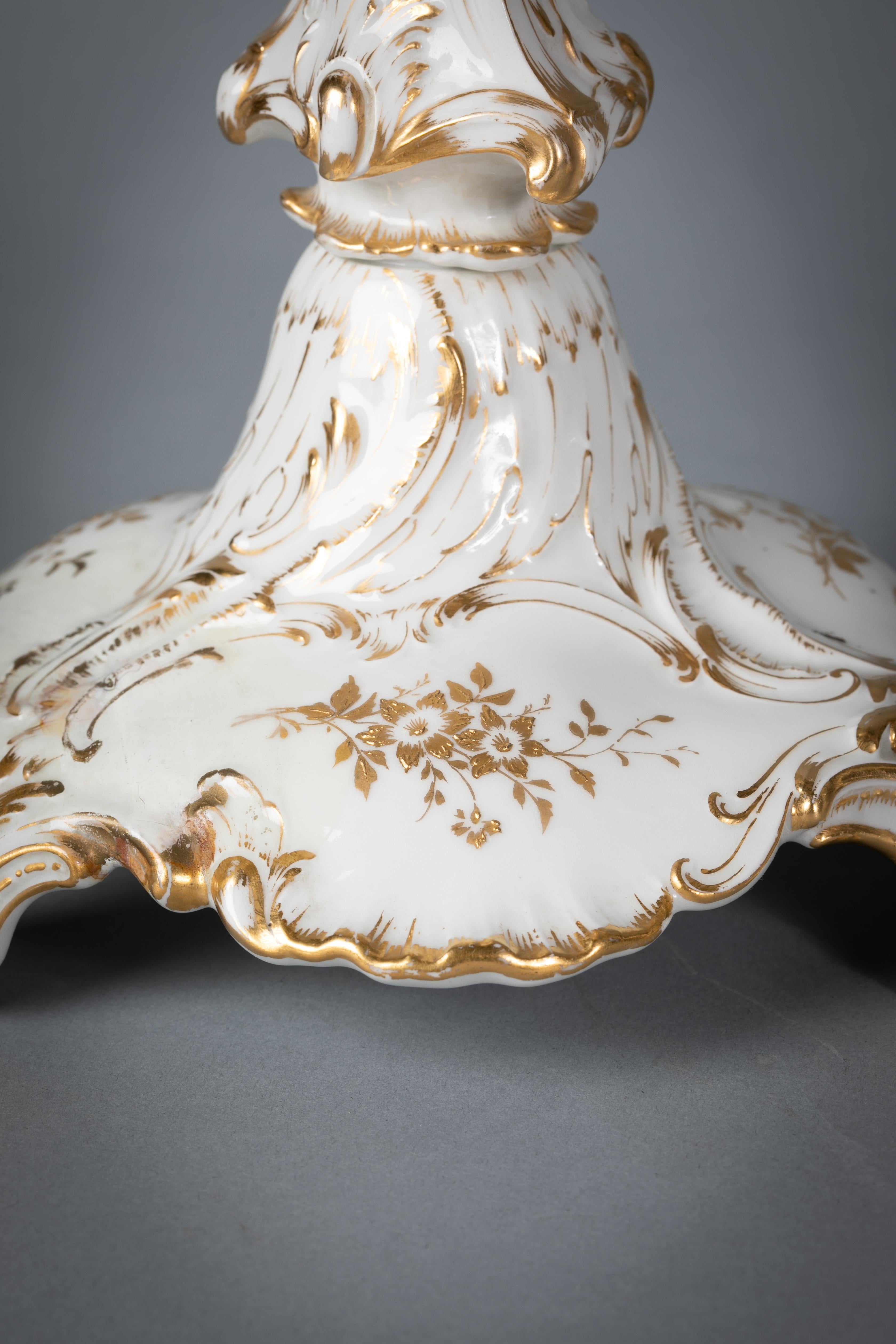 Les chandeliers à décor mouluré et chantourné, peints de rehauts dorés et de rinceaux floraux dorés. Les branches à volutes dorées se terminent par des lèchefrites et des bougeoirs en porcelaine de Berlin. La branche centrale à volutes en bronze est