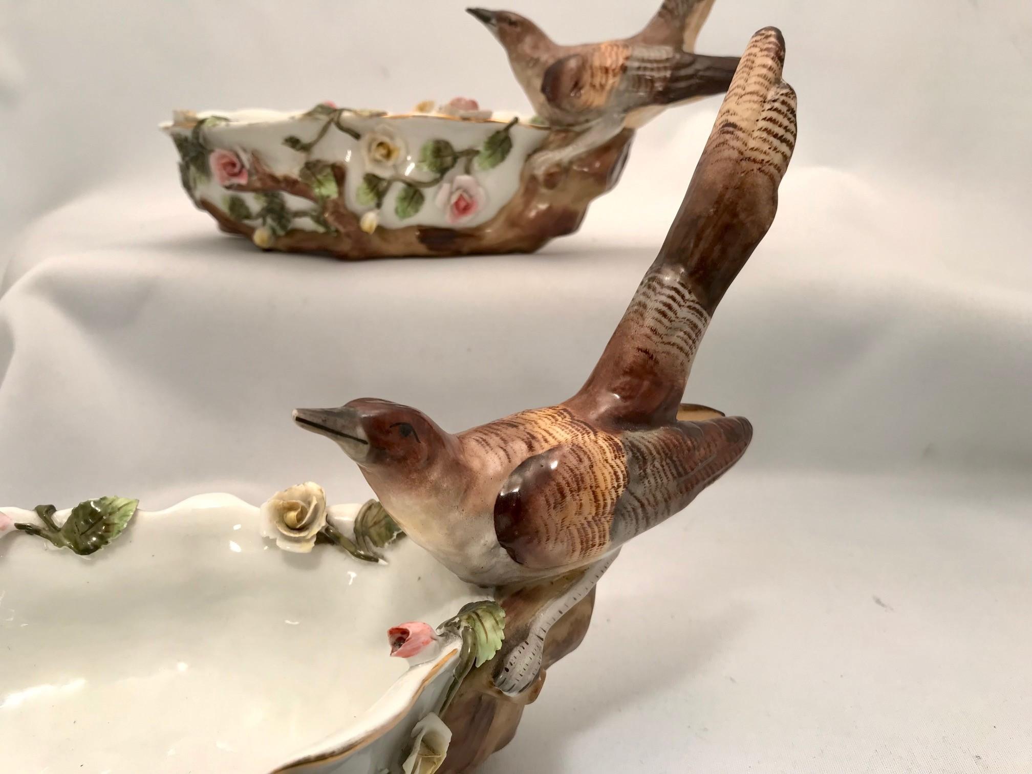 These are porcelain and were made late in the 19th century, probably by Sitzendorf. The edges are scalloped and gilt, the body is applied with rambling roses. The bird is perhaps a thrush.