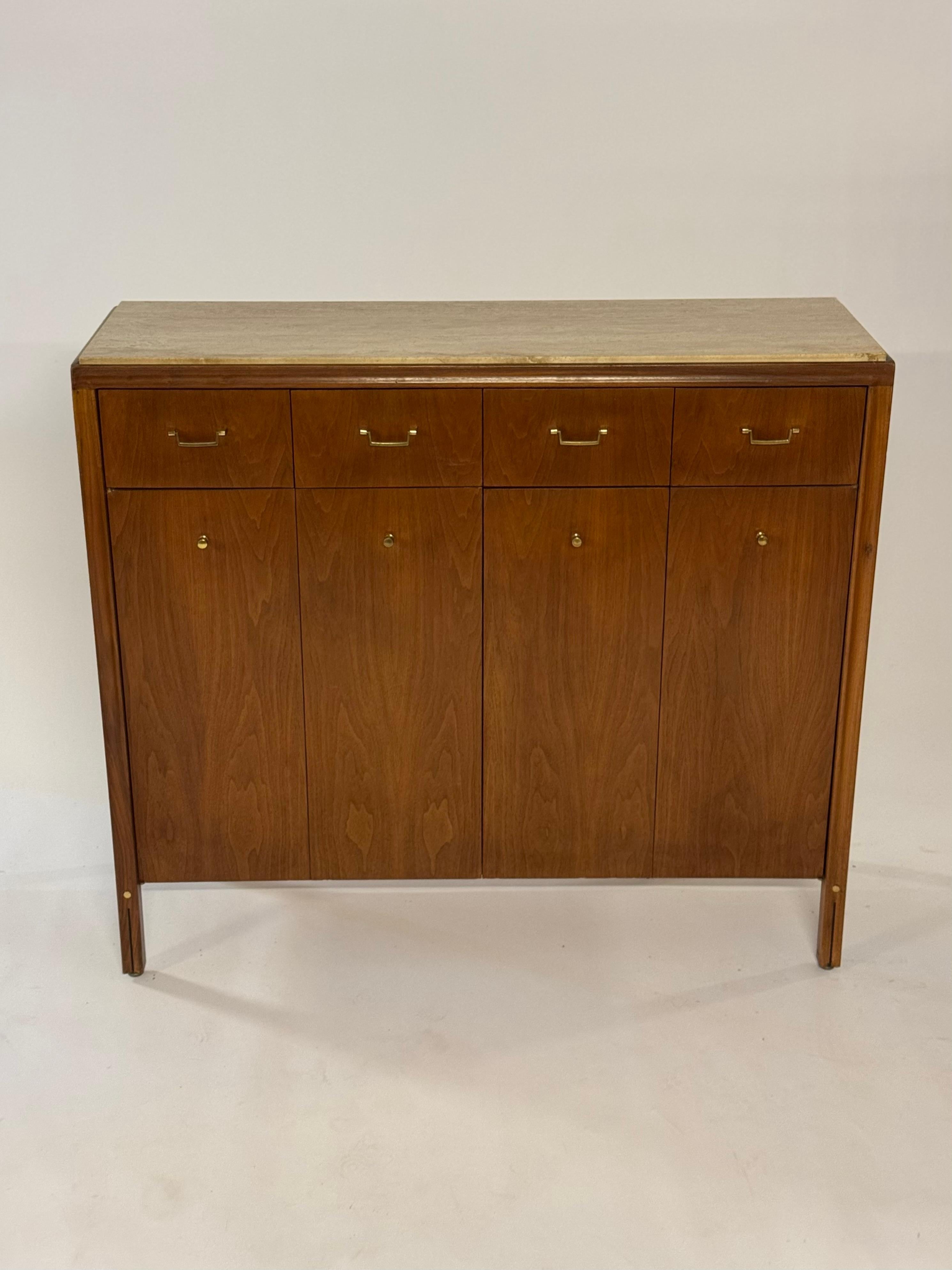 Rara coppia di buffet alti, armadi o credenze della linea Mid-Century Modern Gerry Zanck per Gregori in noce con ferramenta in ottone e piani in travertino. Le porte a due ante si aprono su ripiani regolabili a sinistra e su cinque cassetti