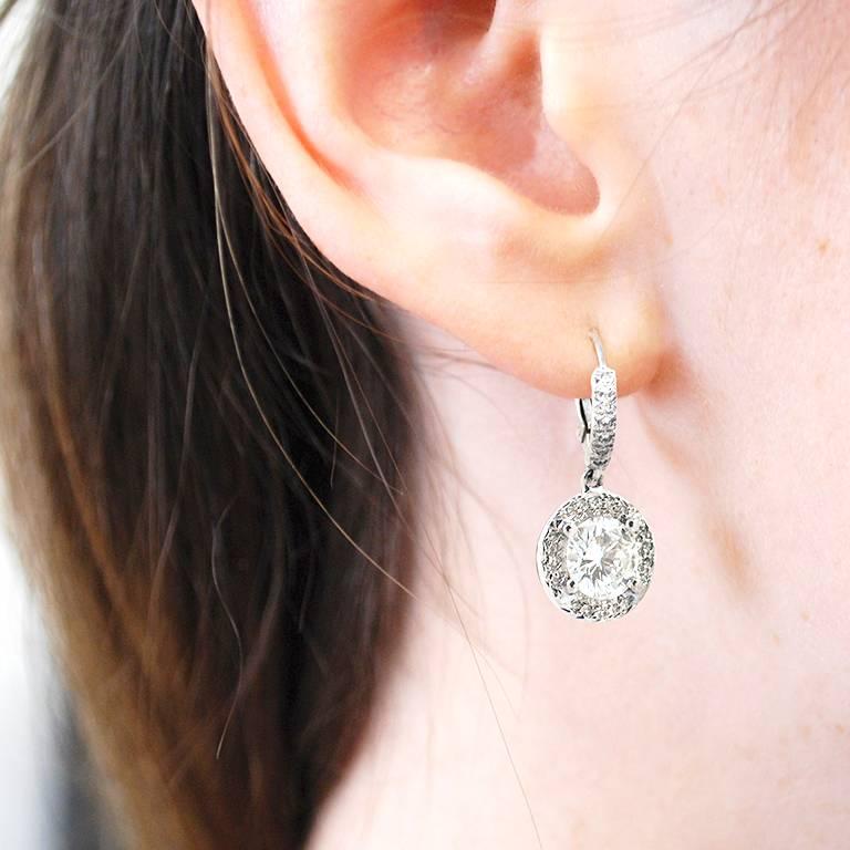 This pair of diamond lever-back earrings is set on 18kt white gold with 0.28 carats of pave diamonds set down each wire. Each earring is set with a GIA certified round brilliant diamond weighing 1.23 carats and 1.17 carats respectively (total 2.40