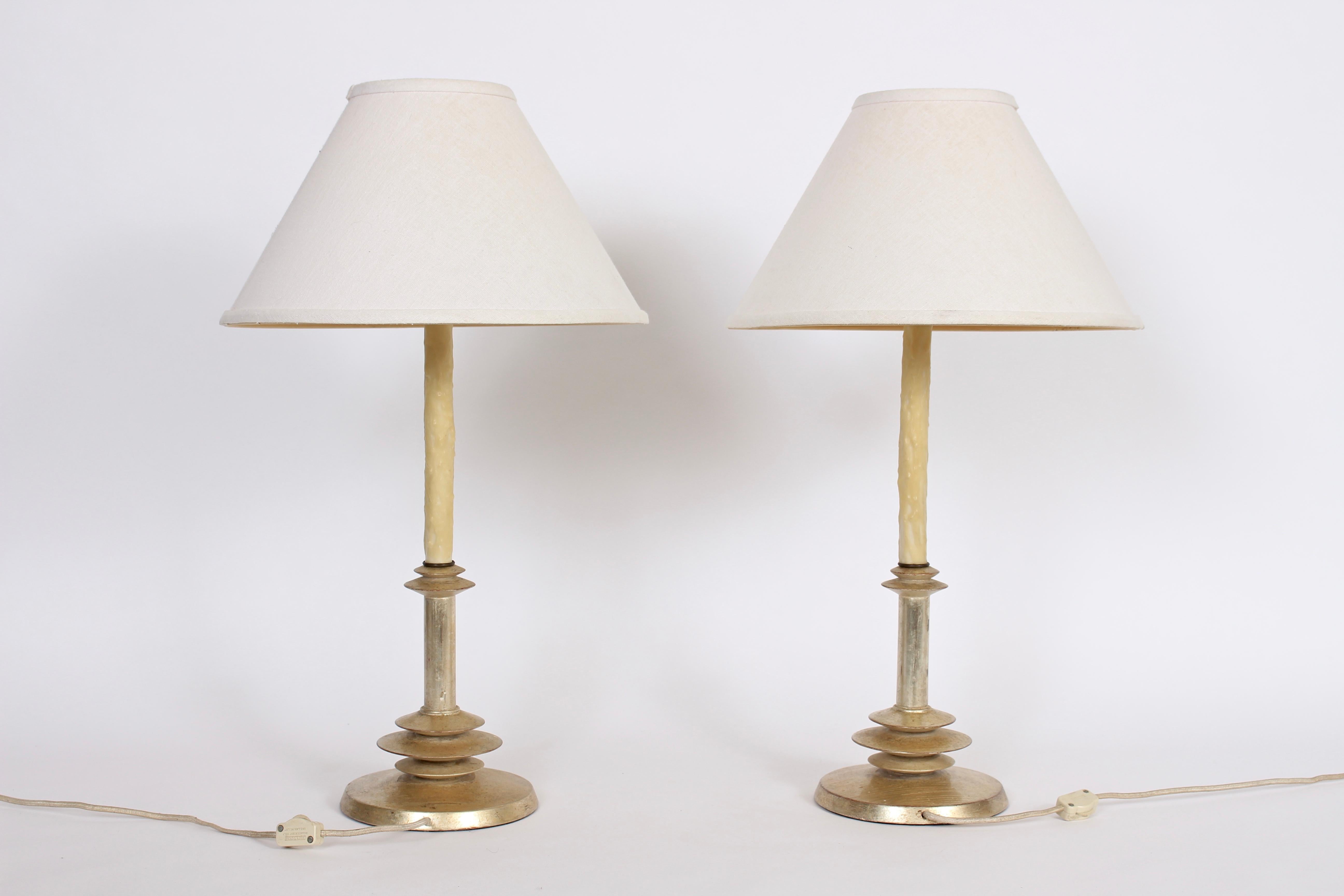 Hollywood Regency pair of Alberto Giacometti style gilt turned wood and waxed candlestick table lamps. Featuring a smooth turned wooden form, luxurious slivered antique gilding and creamed waxed candlestick column. Shades shown for display only (9H