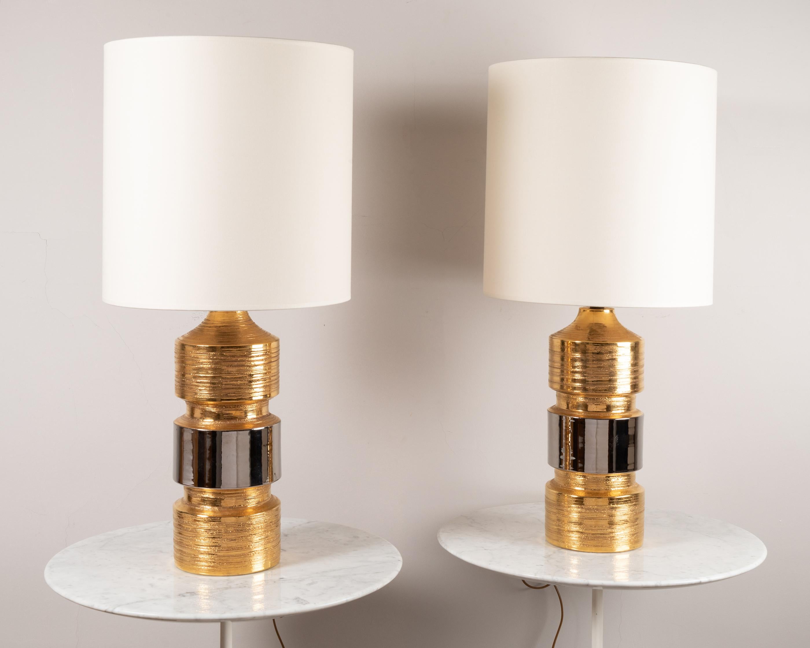 A pair of table lamps,
Gold and silver glazed ceramic with lustre
News shades
Manufactured by Bitossi (Italy)
for Bergboms (Sweden) 
paper labels on both lamps,
Italy, 1960's.