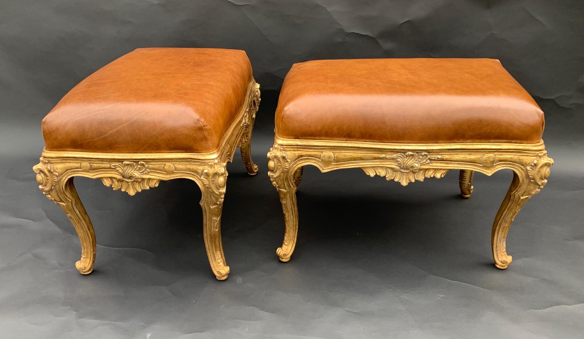 Pair of gild hand carved benches, upholstered in brown leather, Italy, 20th century.