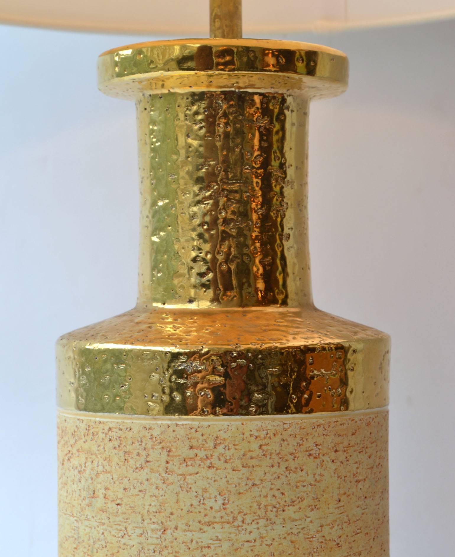 The cylinder shape table lamps where produced in stoneware with a natural glaze. The border at the neck is gilded, the band of shiny gold emphasis the rough texture of the ceramic body.
Guido Bitossi established his own ceramic workshop near