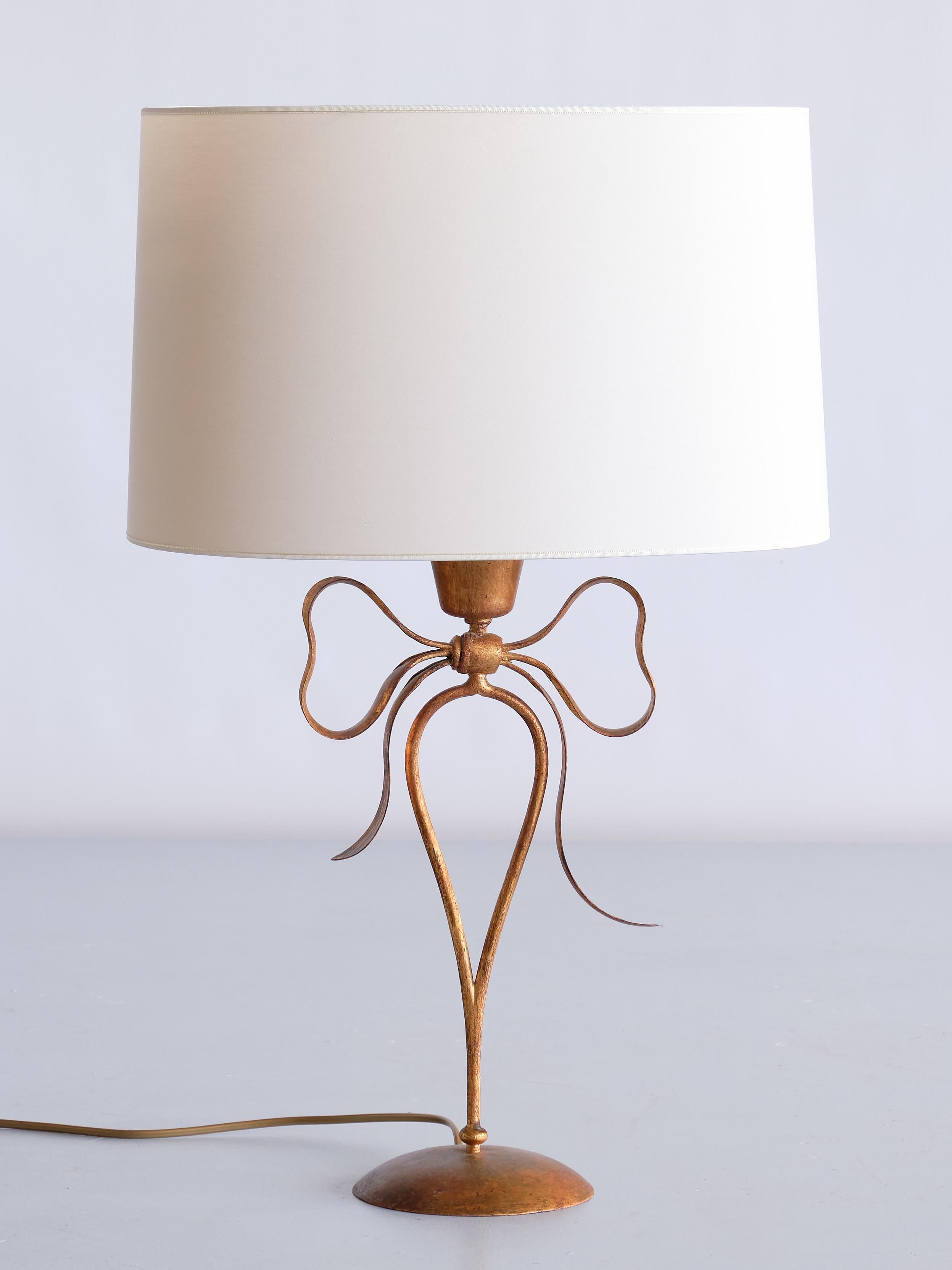This elegant pair of gilded table lamps was produced by the noted Italian artisan ironwork firm Mingazzi of Bologna in the 1950s. The design is marked by the decorative bow shaped body ending in a circular base. The handcrafted lamps are made of