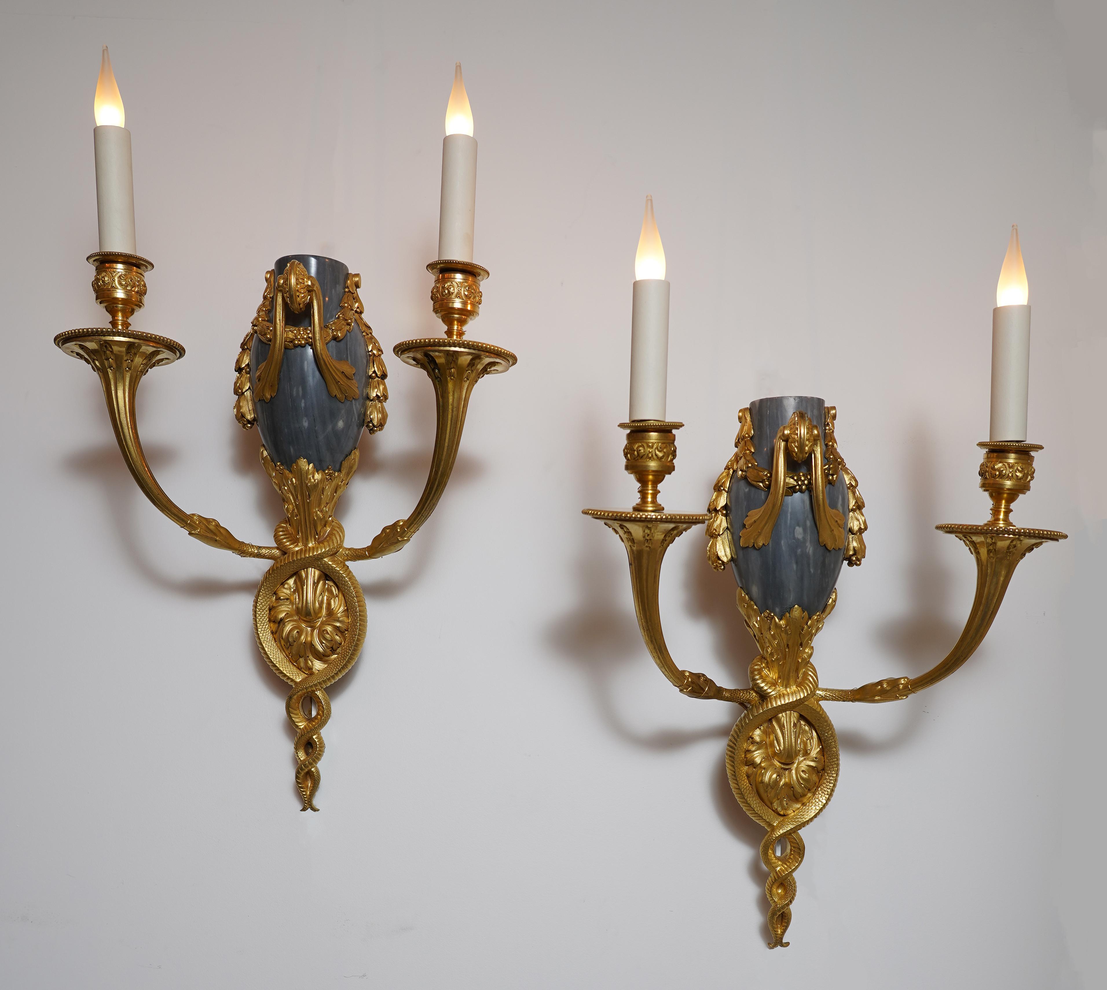 Rare pair of Louis XVI style wall-lights in chiseled and gilded bronze and marble. They are each composed of a barrel made of acanthus leaves supporting a truncated vase in Bleu Turquin marble decorated with a garland of laurel leaves and a leafy