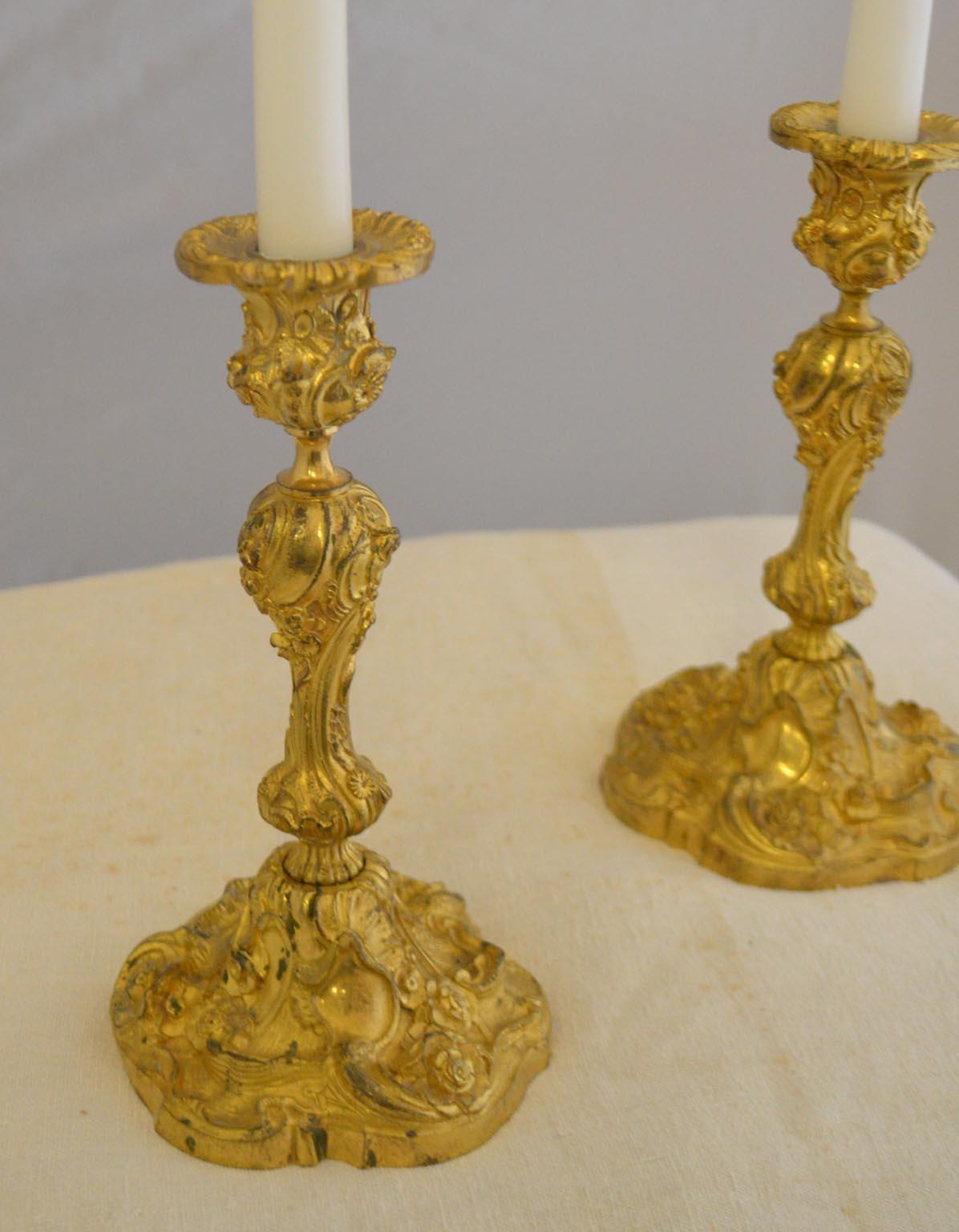 Pair of 19th century Rococo French gilded bronze candlesticks. Good condition. Decorated with foliate scrolled garlands of flowers.