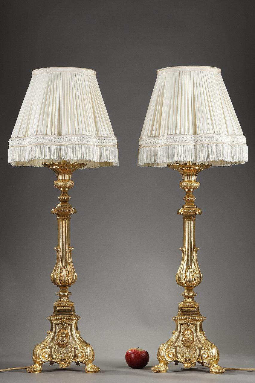 Pair of gilt bronze sculpted and chiseled candlesticks, raised to lampstands, from the 19th century. The base of baluster fluted form is punctuated by small cushions at mid-height, and rests on a tripod base ending on small claw feet. On each side