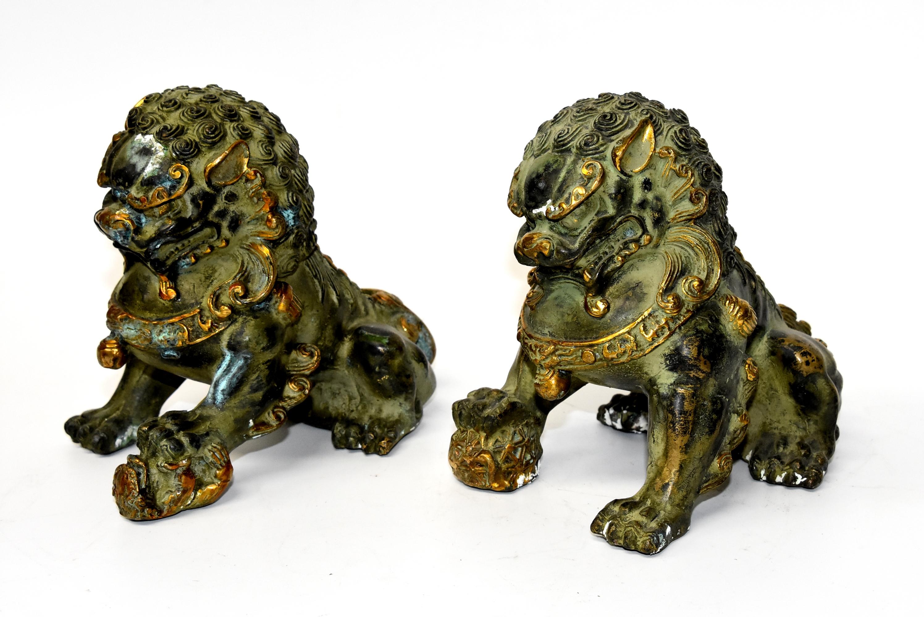 This is a pair of gilded bronze Chinese foo dogs. The male holds a globe firmly in his paw, symbolizing the universe, while the female holds a cub in hers, symbolizing family. The foo dogs' muscles are strong, their hair curly and beautiful, their
