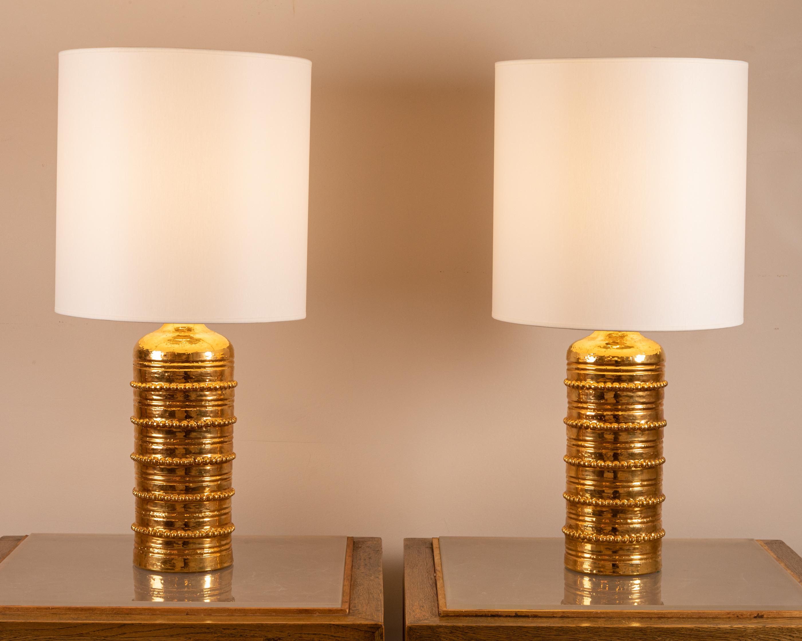 Pair of gild enamelled ceramic lamps.
The cylindrical body adorned with 5 strings of pearls.
By Bitossi for the Swedish market, retailed by Bergboms
Italie, 1960

Dimensions :

Total height ( With Shades ) : 72 cm ( 28,34 inch)
Height (