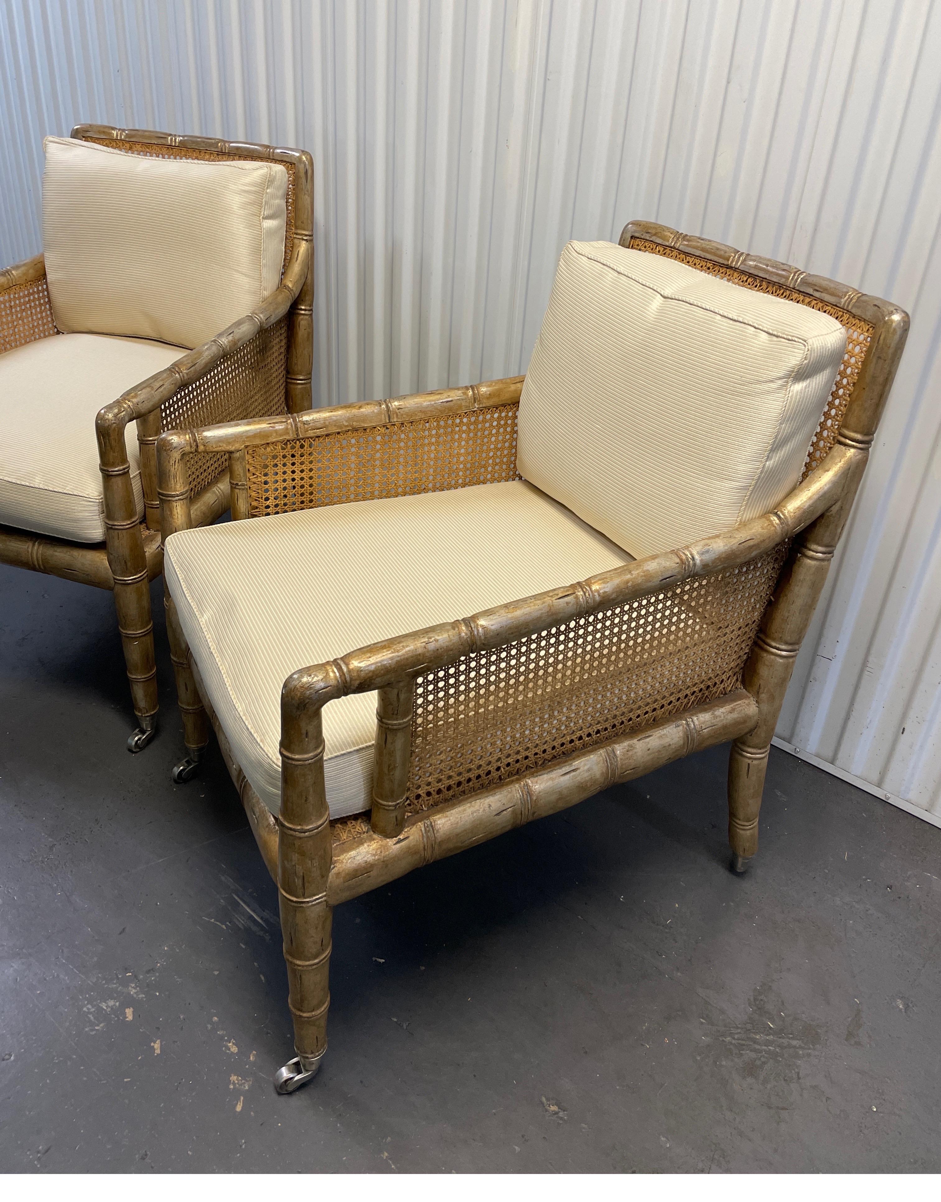 Vintage pair of gilded Hollywood Regency style faux bamboo & cane armchairs on castors with bone silk cushions.