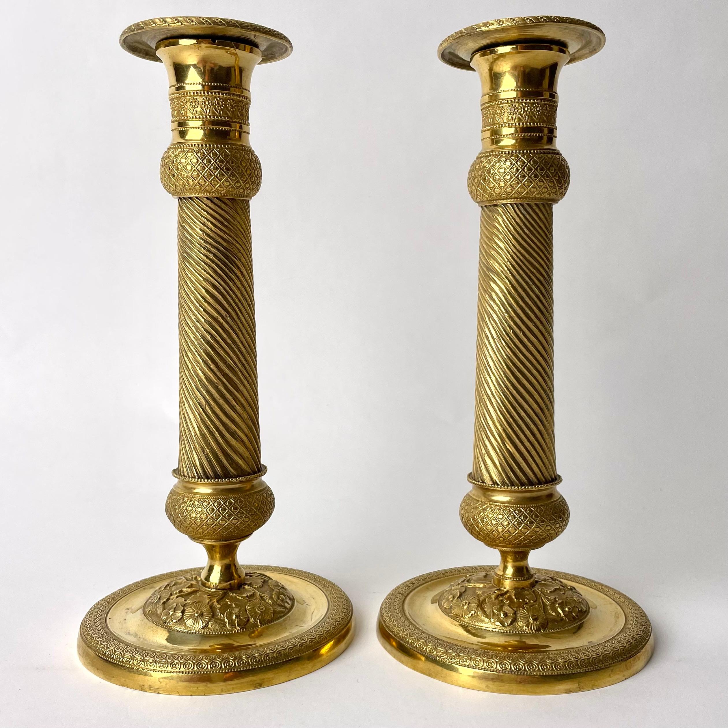  Ein Paar vergoldete französische Empire-Kerzenleuchter mit charmantem Dekor aus den 1820er Jahren. Wunderschön verziert mit Blumen und anderen Dekorationen aus dem Kaiserreich.

Abnutzung entsprechend dem Alter und dem Gebrauch 