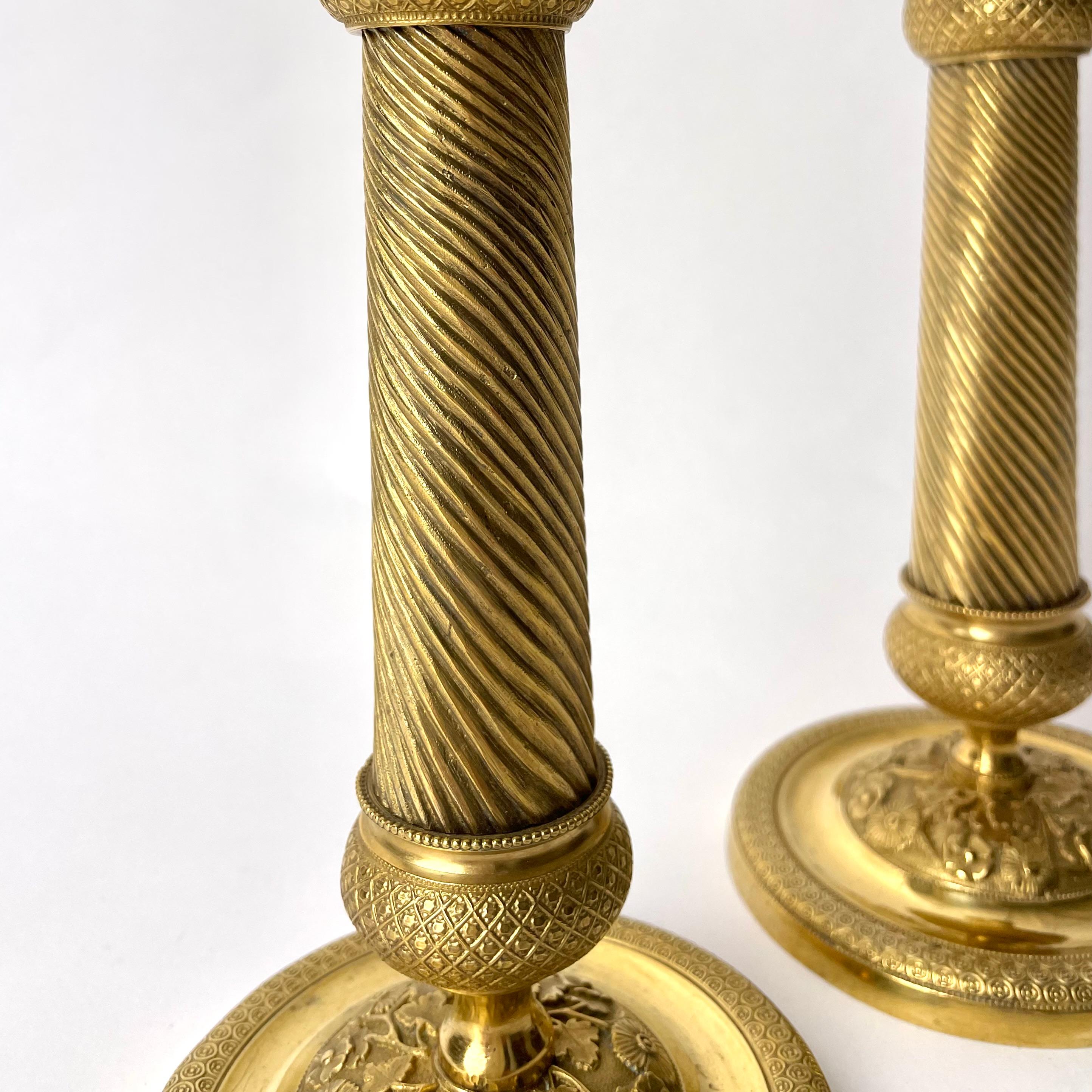 Bronze Pair of Gilded French Empire Candlesticks with charming decor from the 1820s For Sale