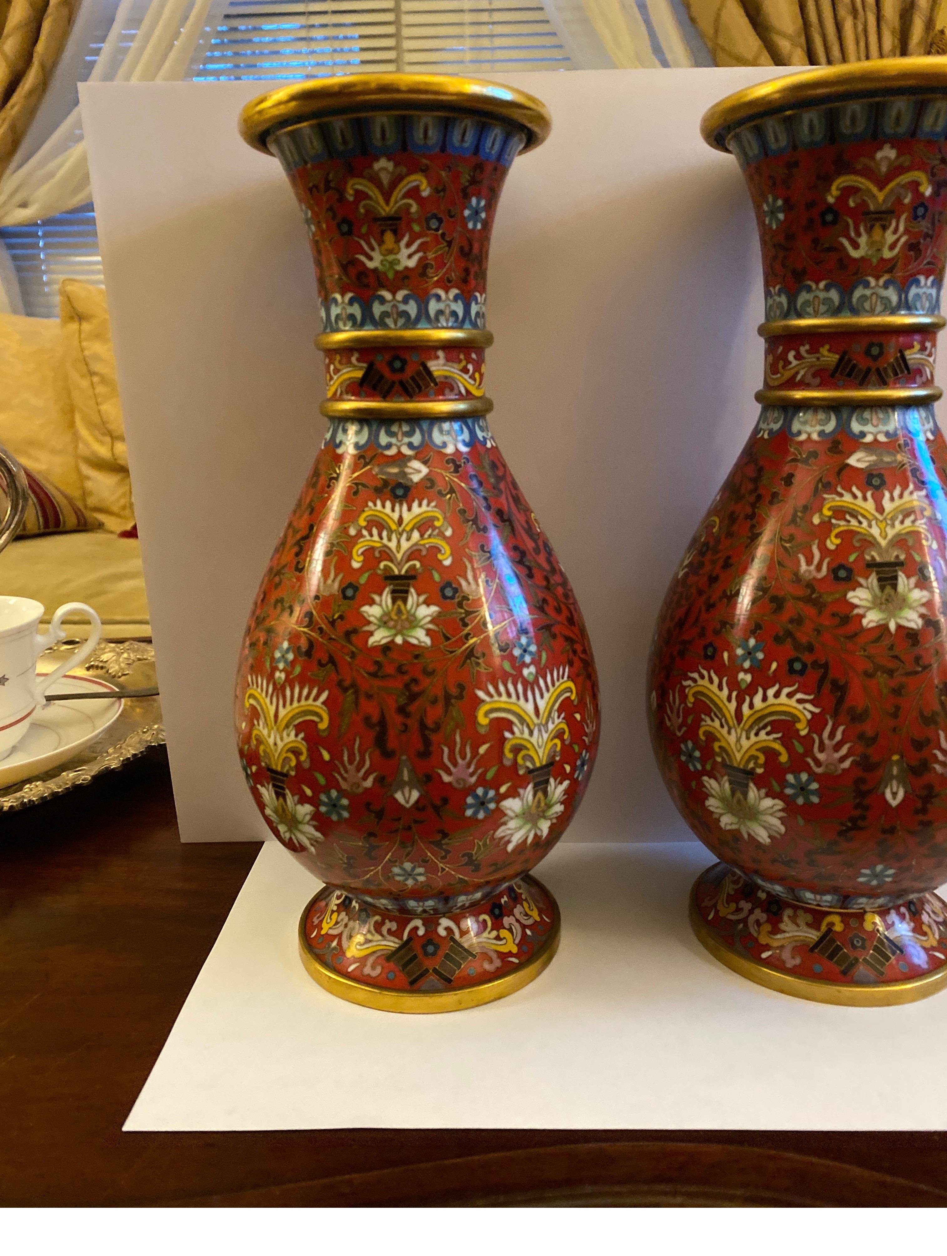 This pair of cloisonné enameled vases was created in Japan, mid-20th century. Each vase with elegant form features a gilt brass bottom ring, two gilt brass rings around the neck and one at the top. The pieces have dark rich cinnabar red ground
