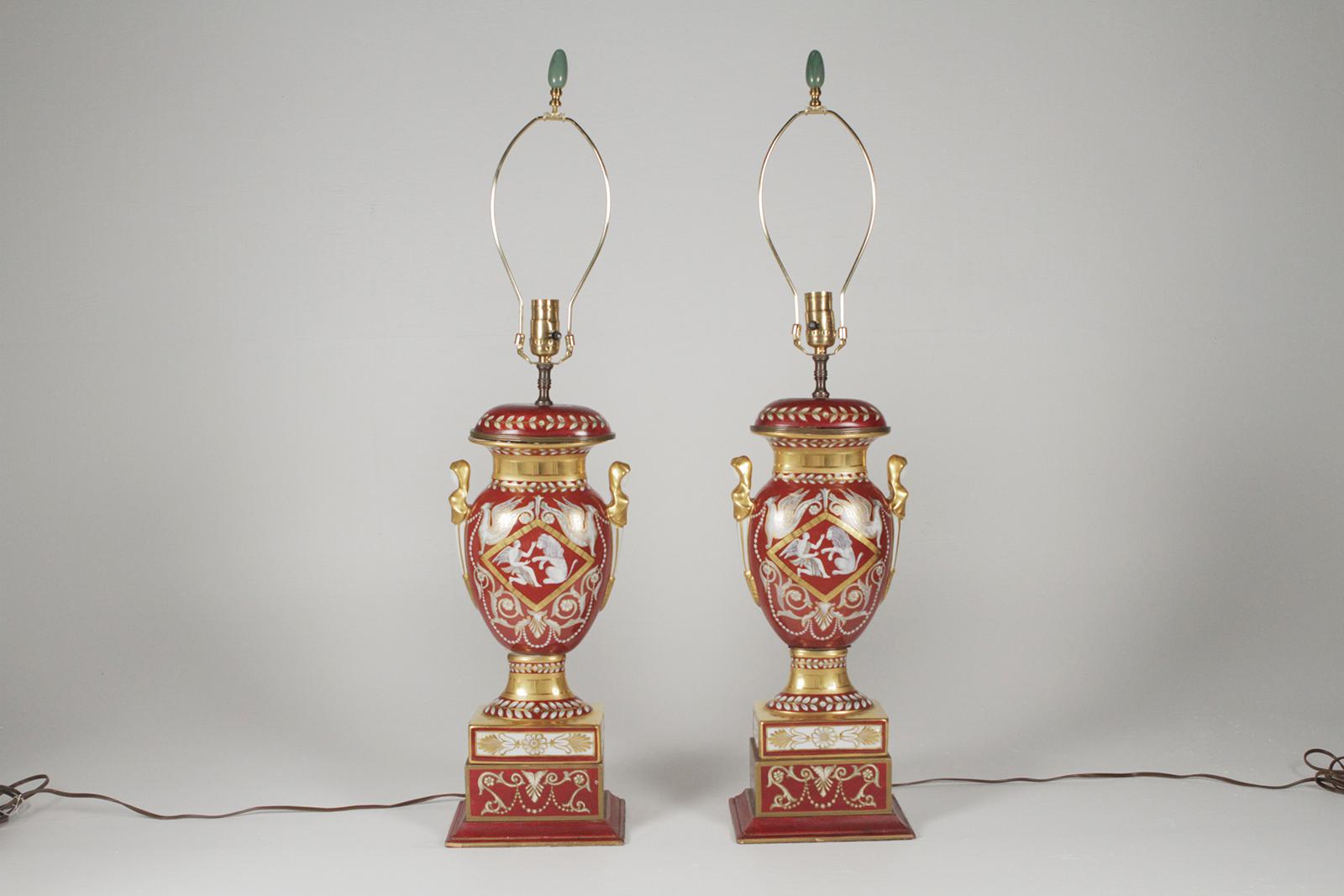 Pair of Gilt And Painted Porcelain Table Lamps Circa Early 1900’s With Mythological Decorations. Vibrant iron red background with sumptuous gilding all over. The shades are for Photographic purposes only and NOT included with these lamps.m