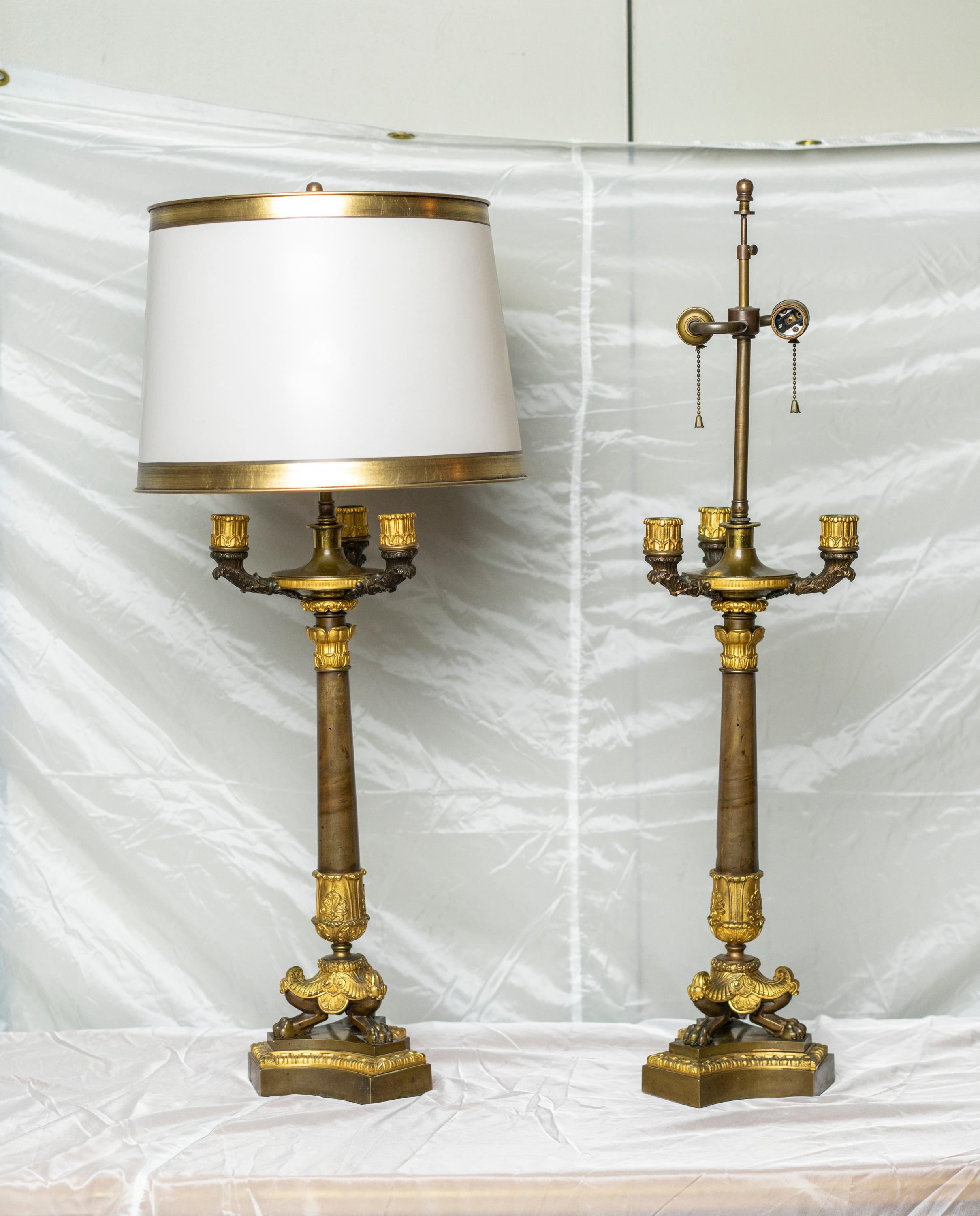 Pair of gilt and patinated bronze Restauration period candelabra lamps
The upper part in antique urn, the arms with acanthus leaves, resting on a tripod base with claw feet surmounted by palmettes.