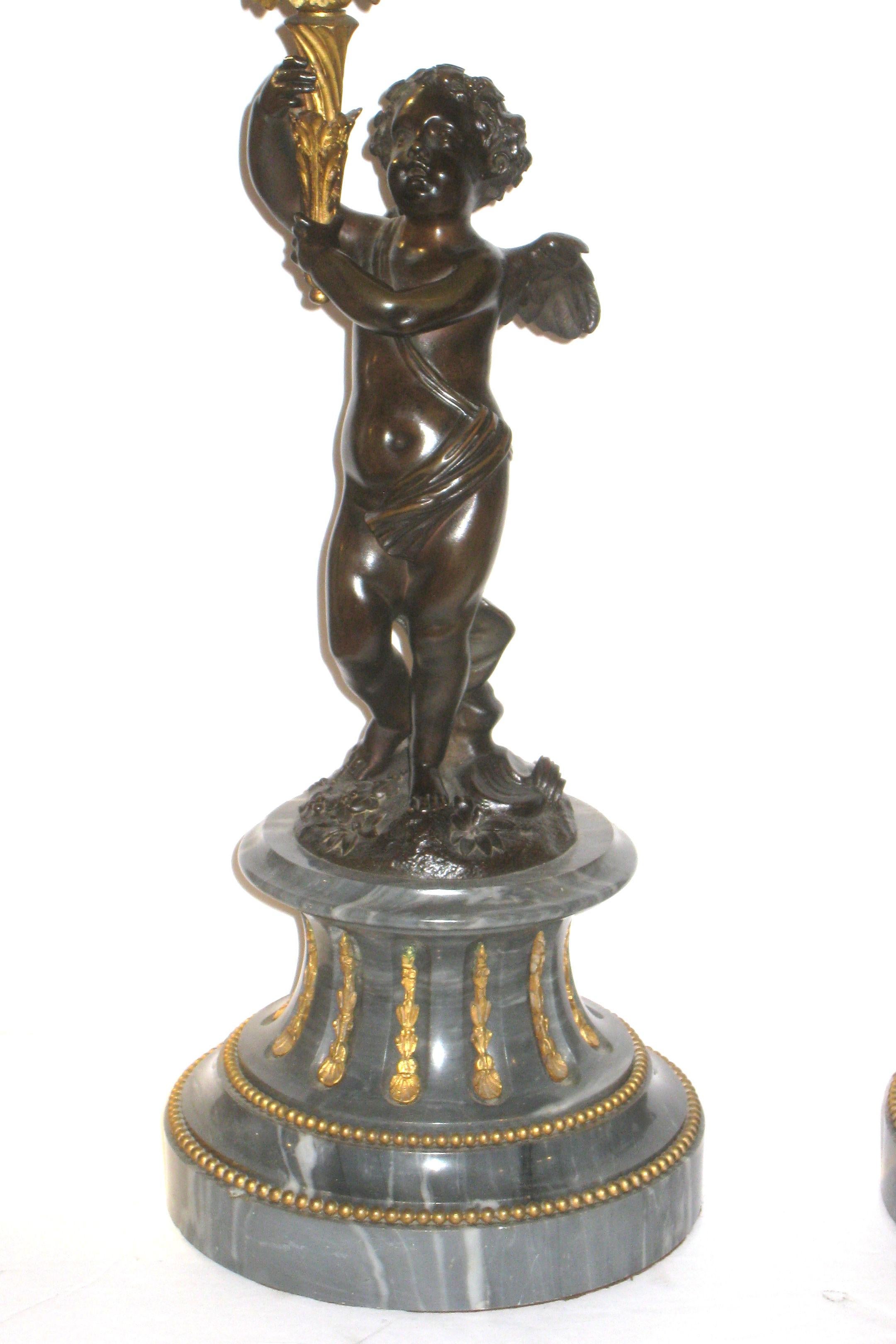 Pair of French 19th century Louis XVI style gilt and patinated figural bronze and marble candelabras with cherub motifs.