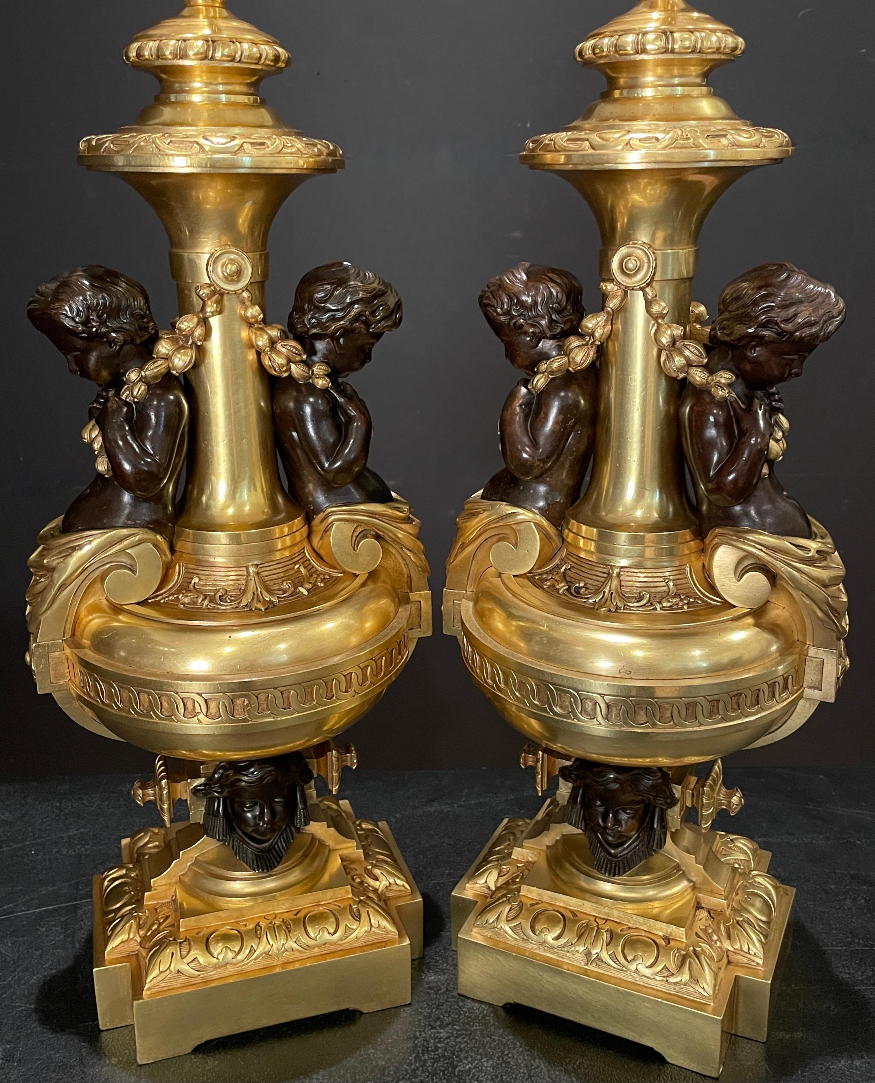 A rare and wonderful pair of French 19th century ormolu garnitures as lamps. Gilt urns with patinated putti torso in caryatid form holding garland seated on a base with cherub faces. Of large and full stature. Finest quality with beautiful doré and